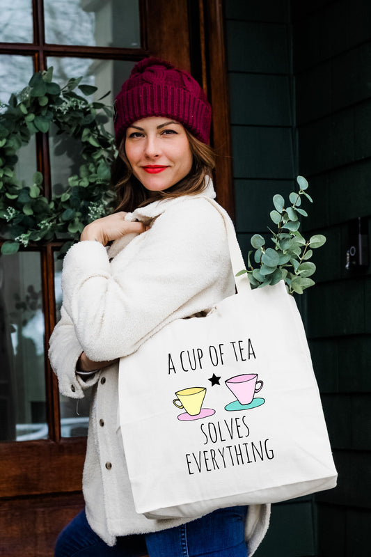a woman carrying a bag that says a cup of tea solves everything
