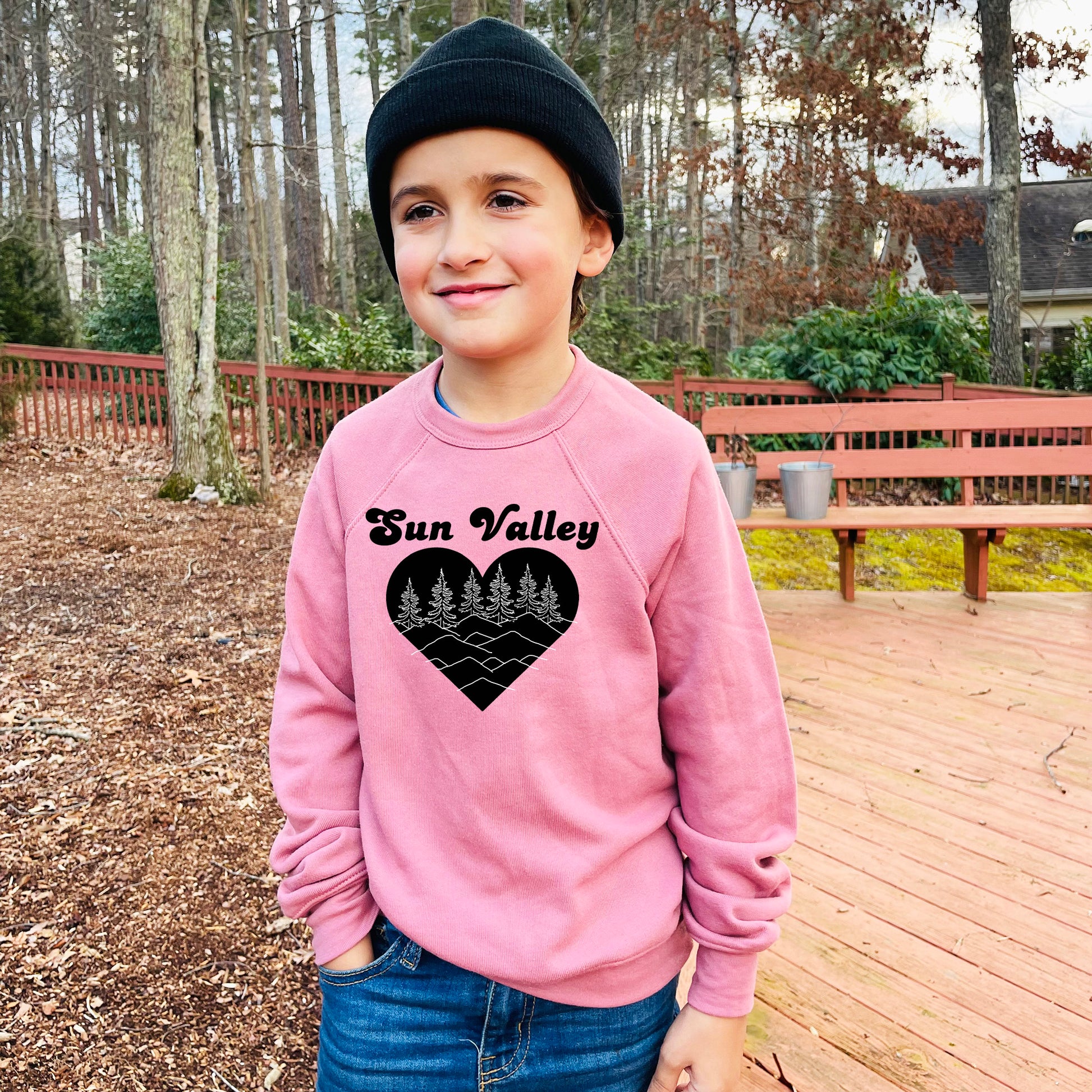 a young boy wearing a pink sun valley sweatshirt