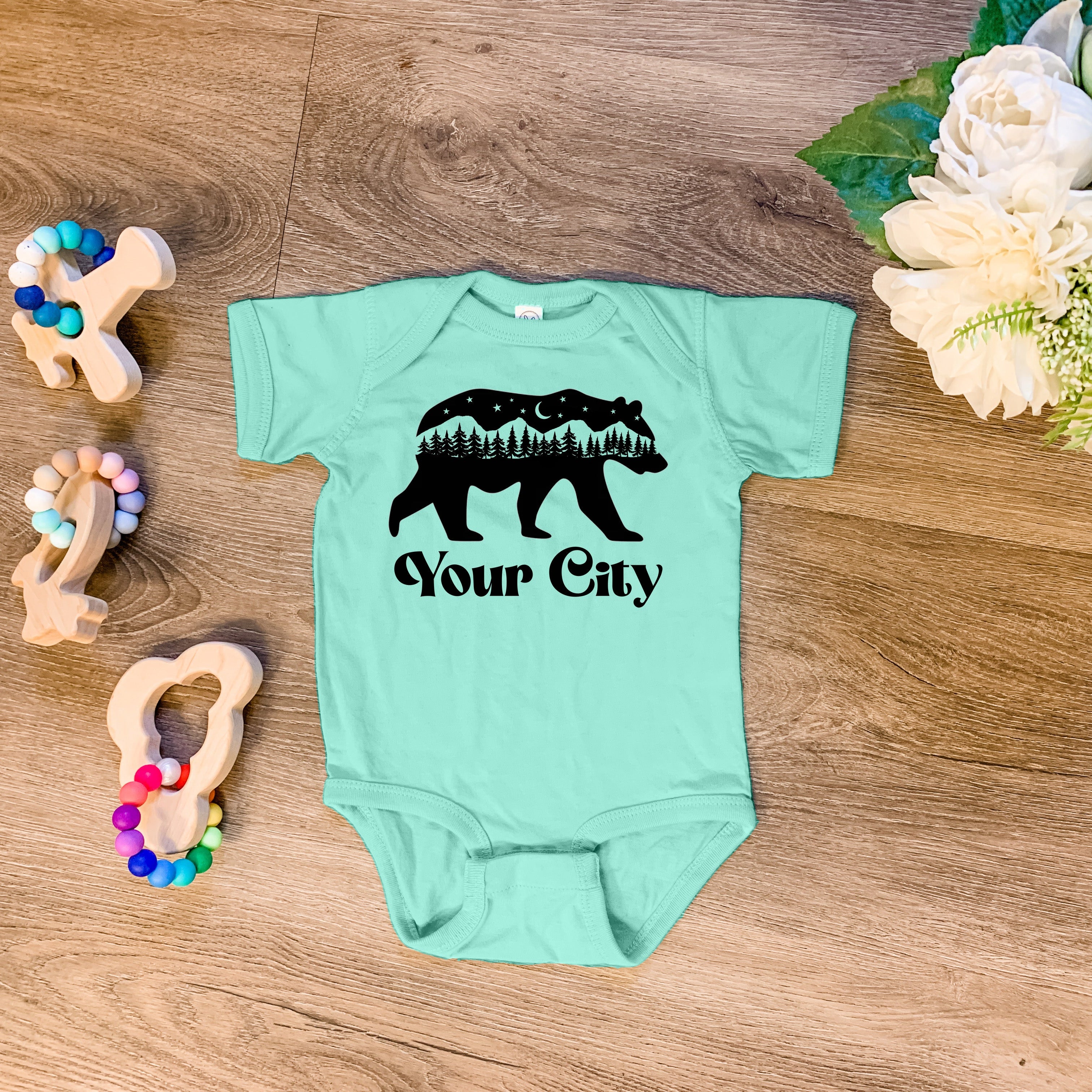a baby bodysuit with a bear and trees on it