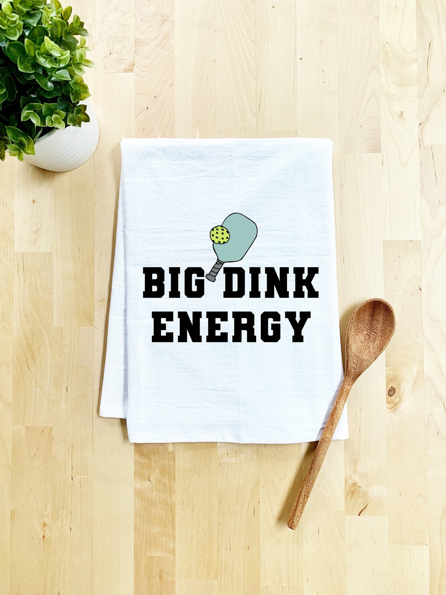 a dish towel that says big dink energy next to a wooden spoon