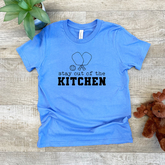 a blue shirt that says stay out of the kitchen next to a teddy bear
