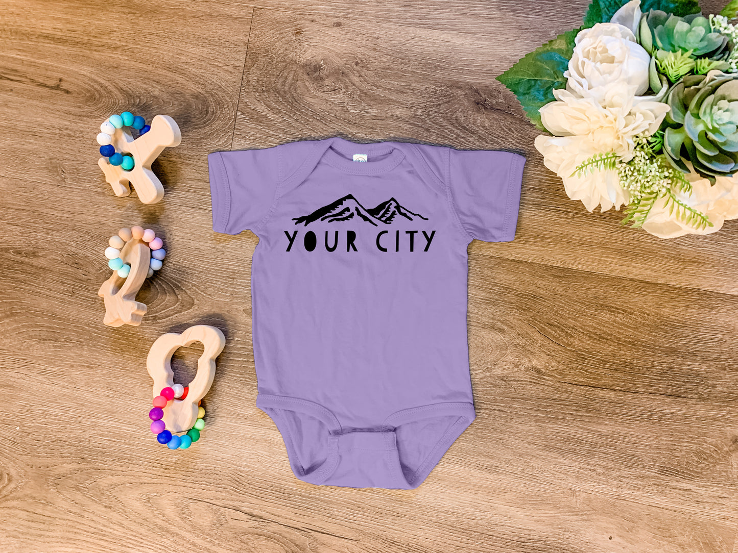 a baby bodysuit sitting on top of a wooden floor