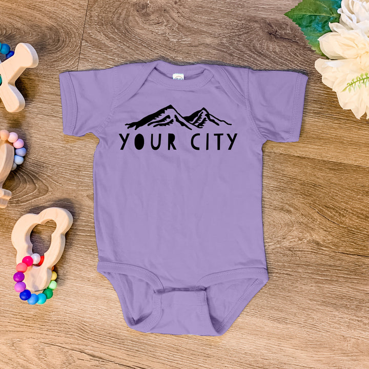 a baby bodysuit sitting on top of a wooden floor