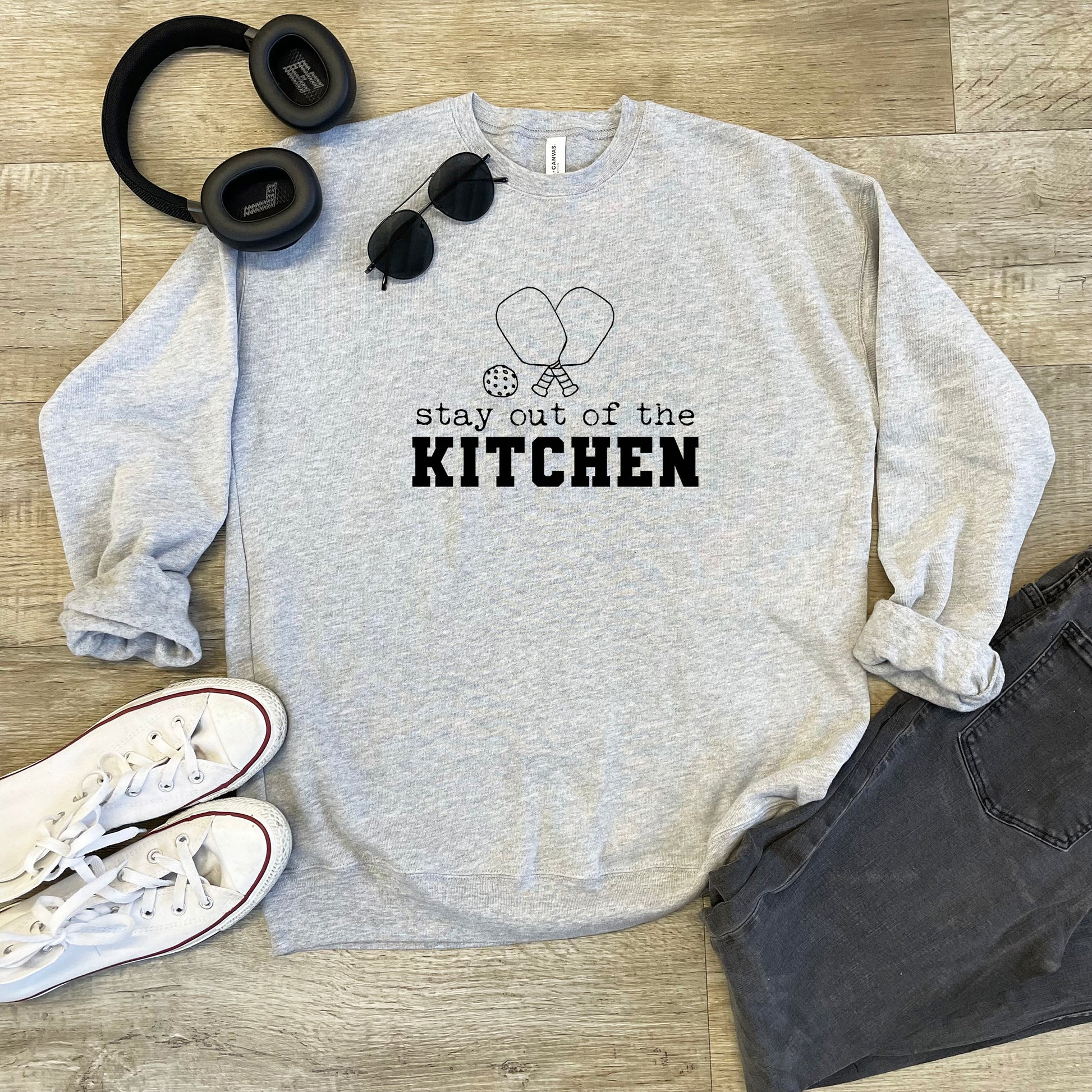 a sweatshirt that says stay out of the kitchen next to headphones