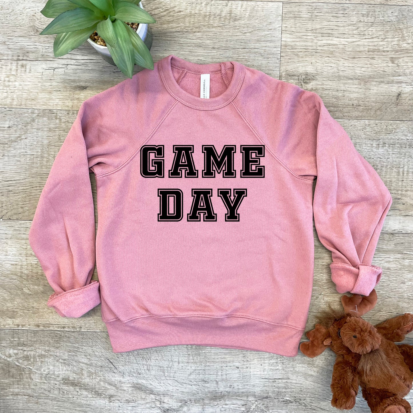 a pink sweatshirt that says game day next to a teddy bear