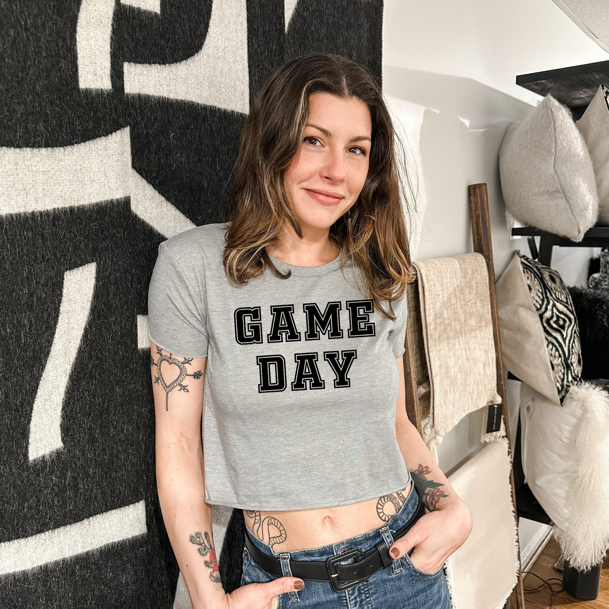 a woman standing in front of a wall with a game day shirt on