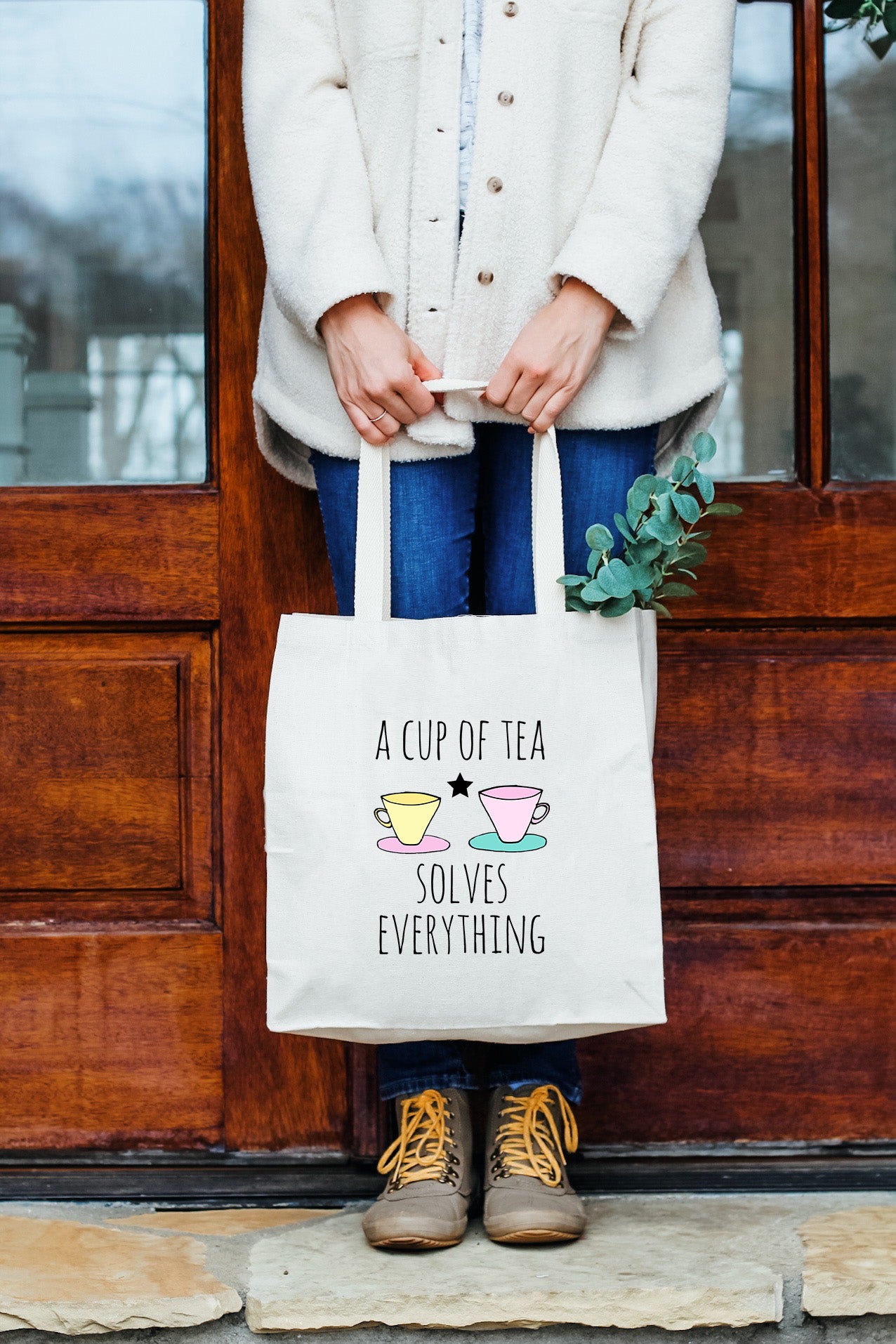 a woman holding a bag that says a cup of tea solves everything