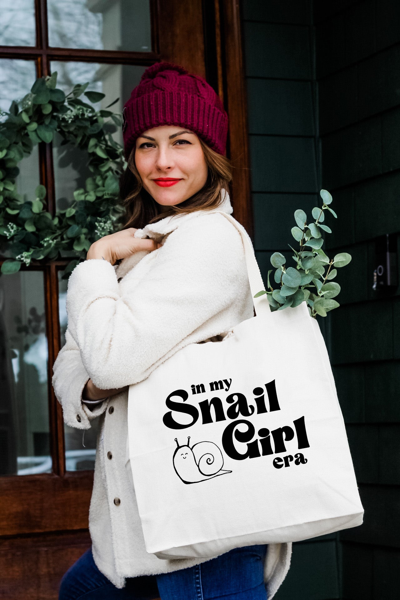 a woman carrying a white bag with a snail girl logo on it