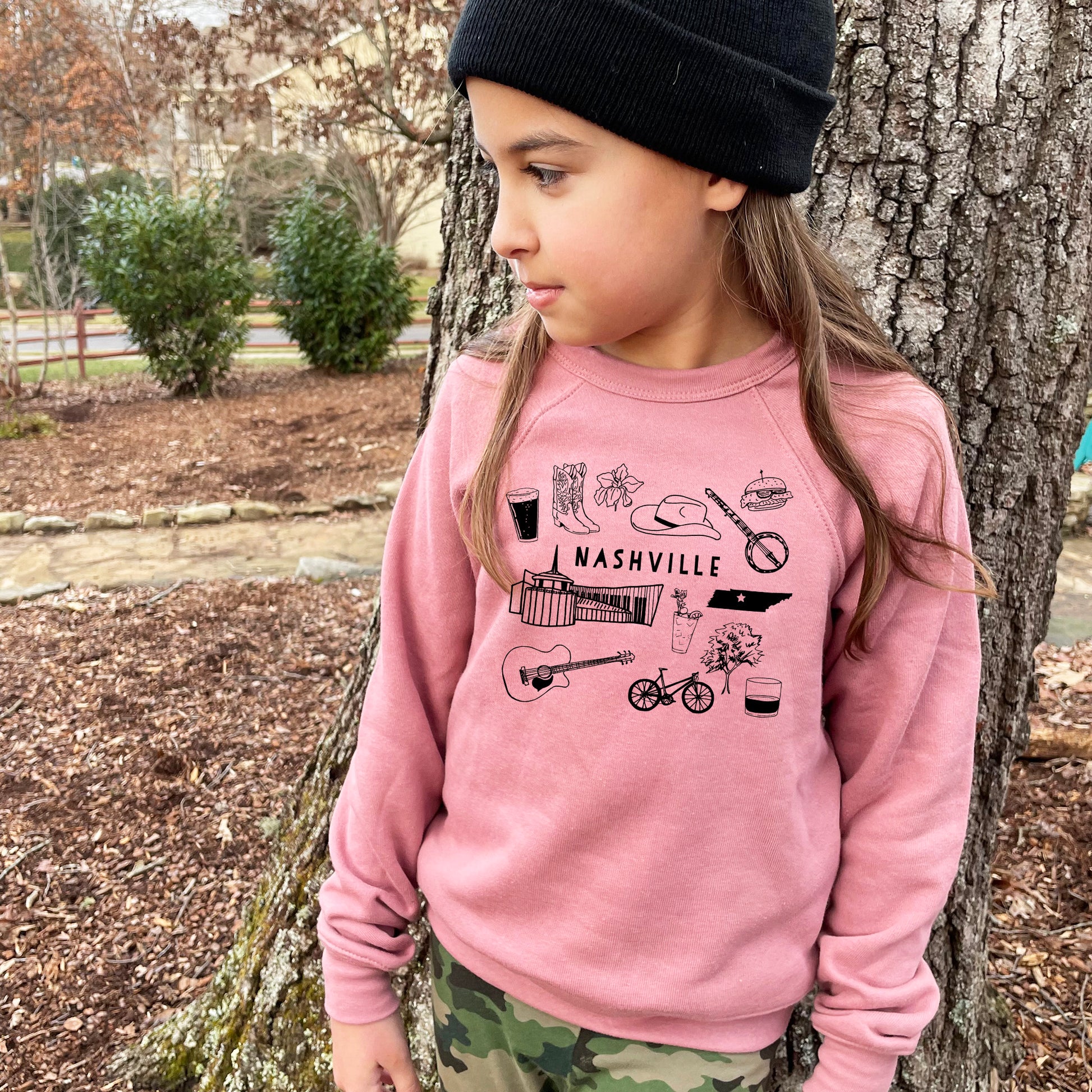 a little girl standing next to a tree