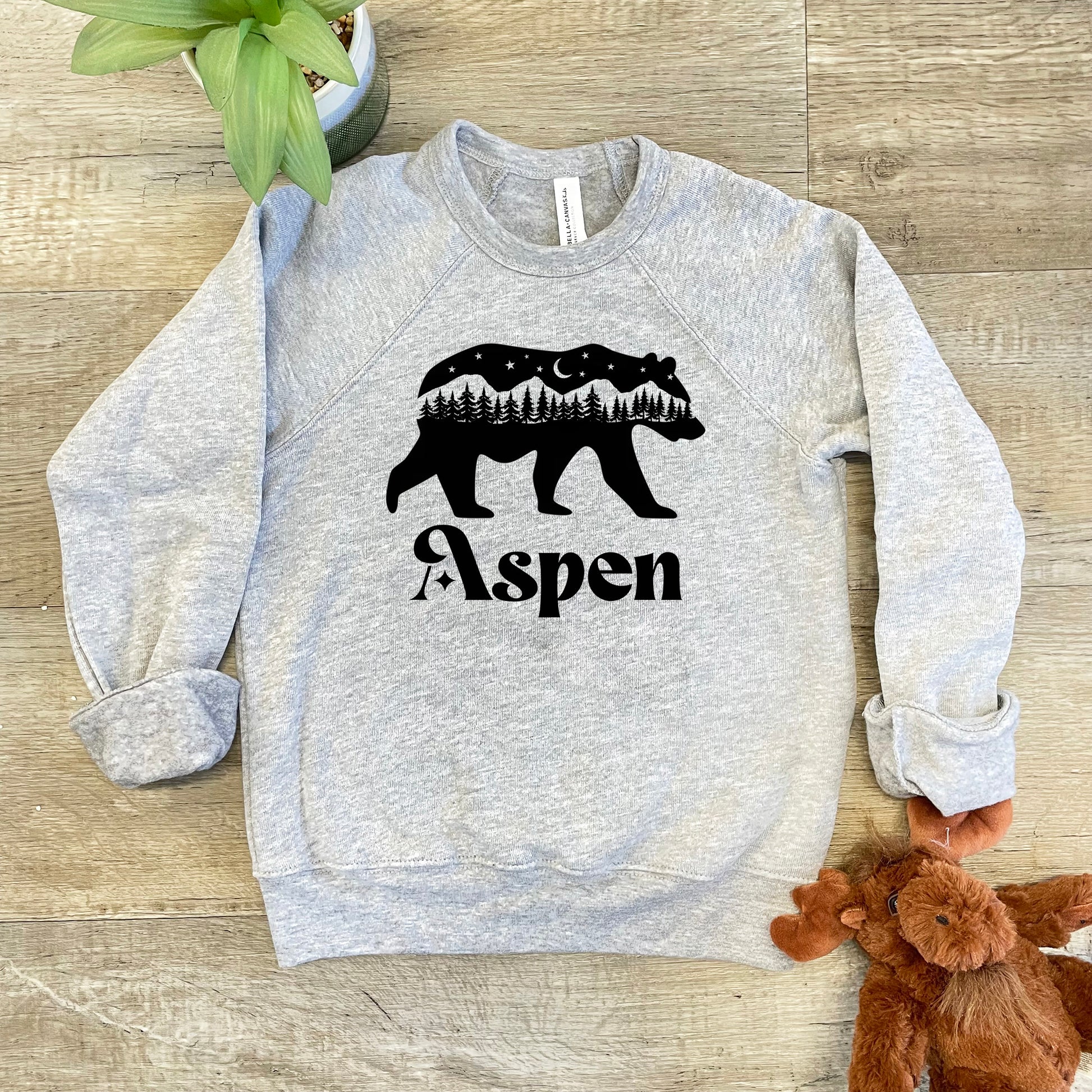 a grey sweater with a bear and trees on it