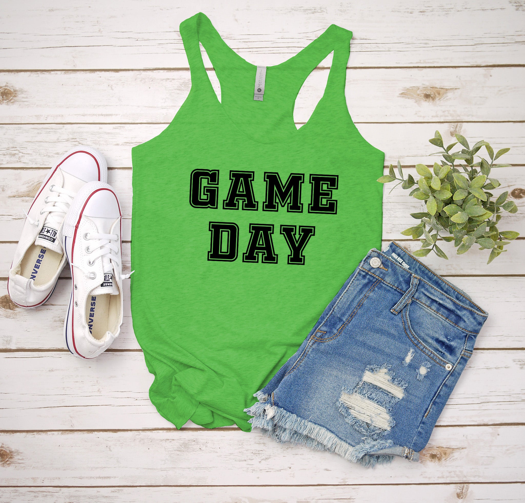a green tank top that says game day next to a pair of shorts