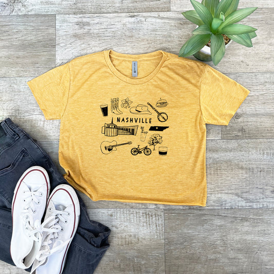 a yellow nashville t - shirt sitting on top of a wooden floor