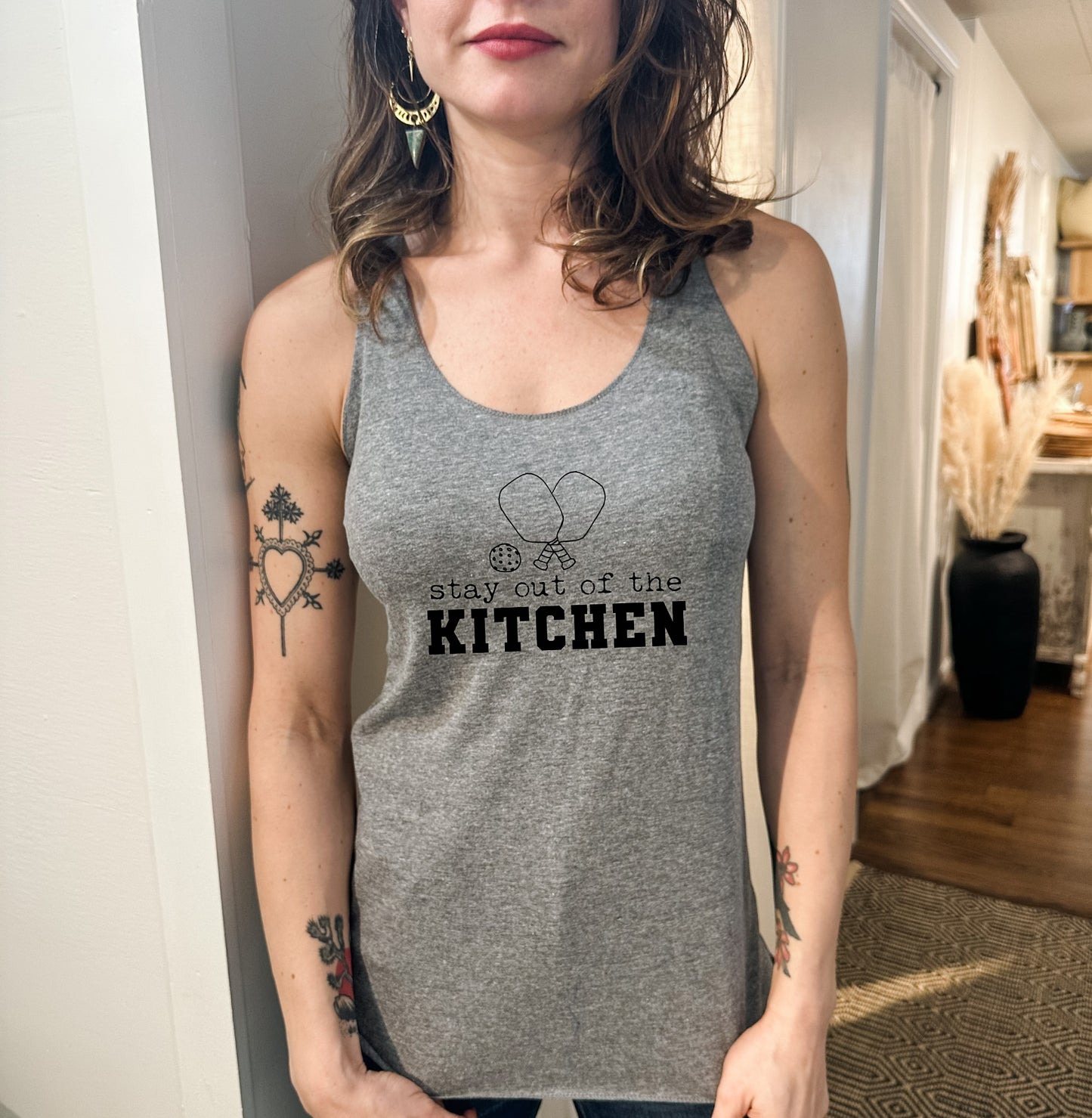 a woman wearing a gray tank top with the words stay out of the kitchen on