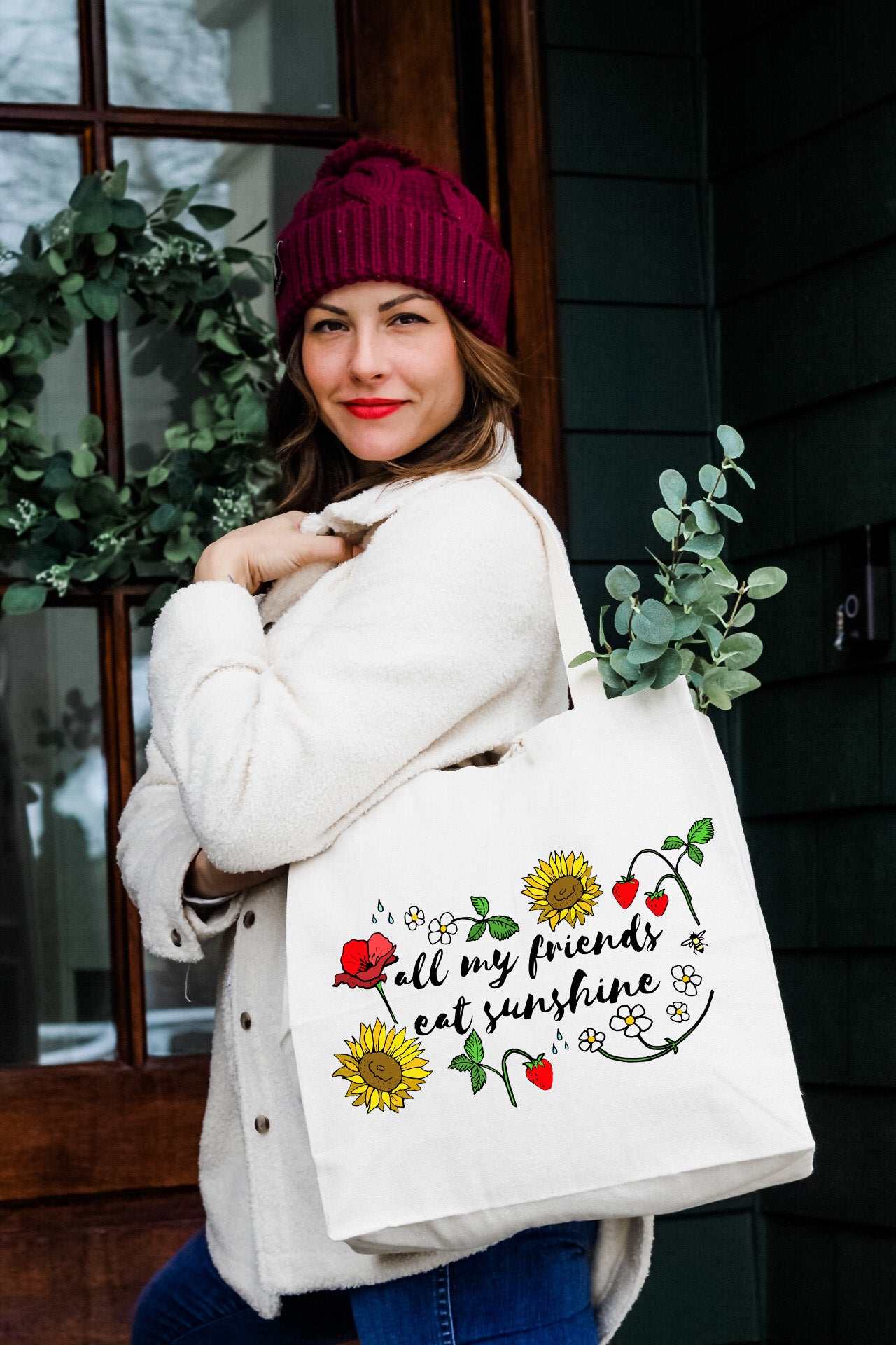 a woman carrying a white bag with a sunflower design