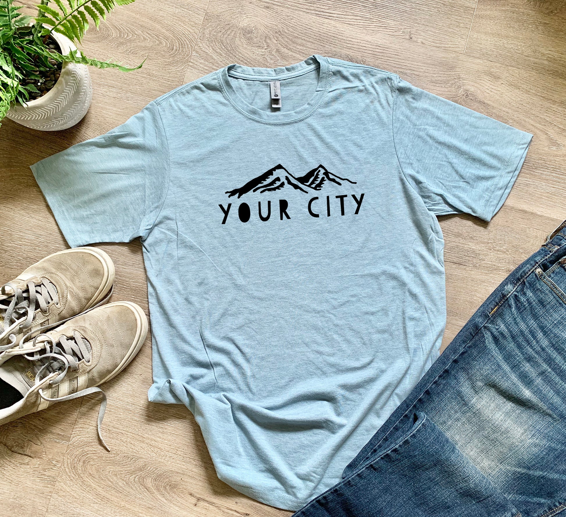 a t - shirt that says your city on it next to a pair of jeans