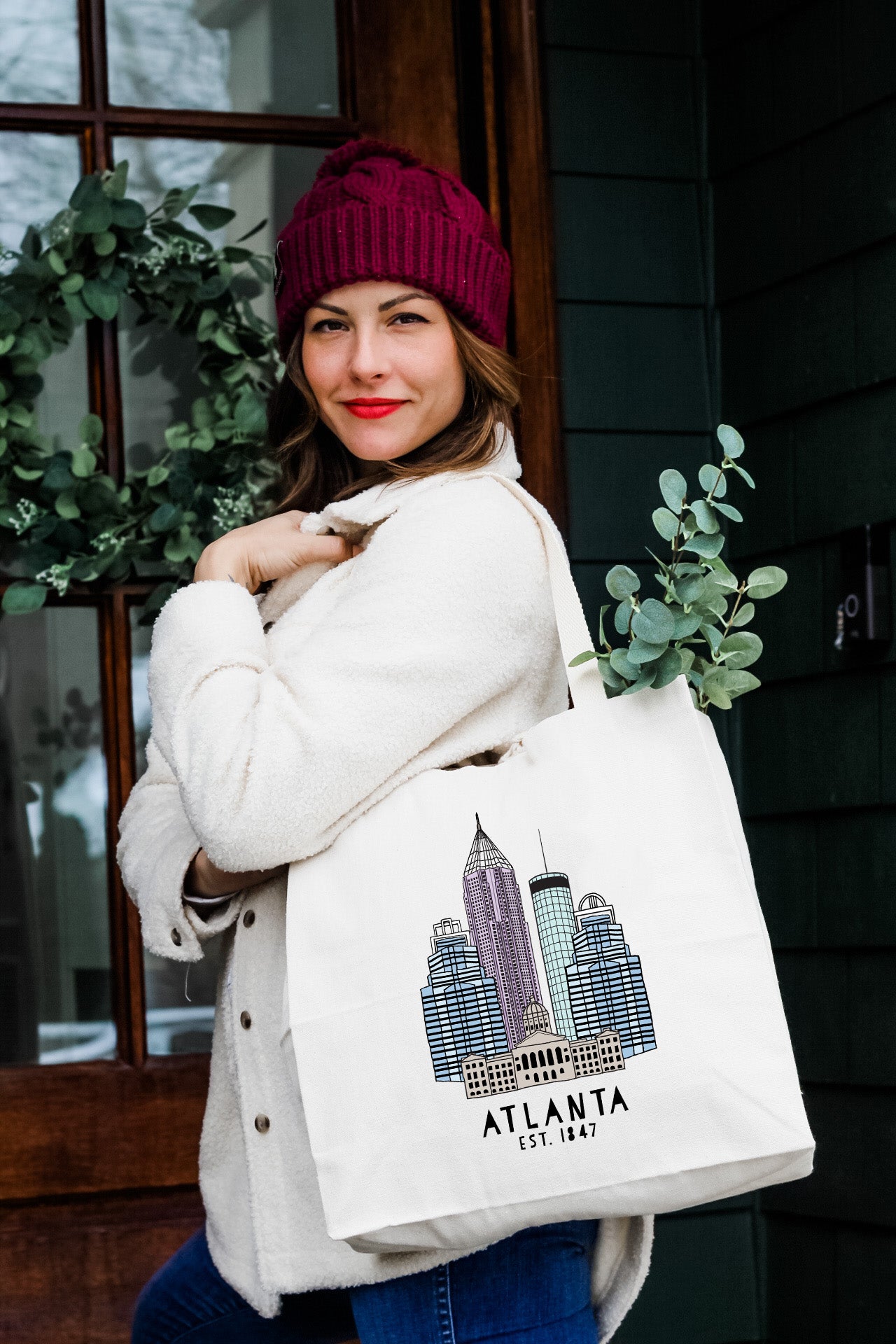 a woman carrying a white shopping bag with atlanta skyline on it
