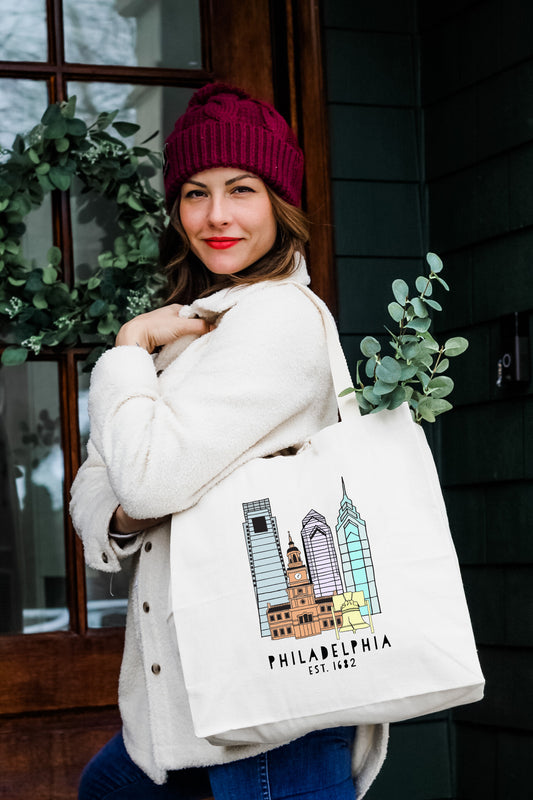 a woman carrying a white bag with a picture of philadelphia on it