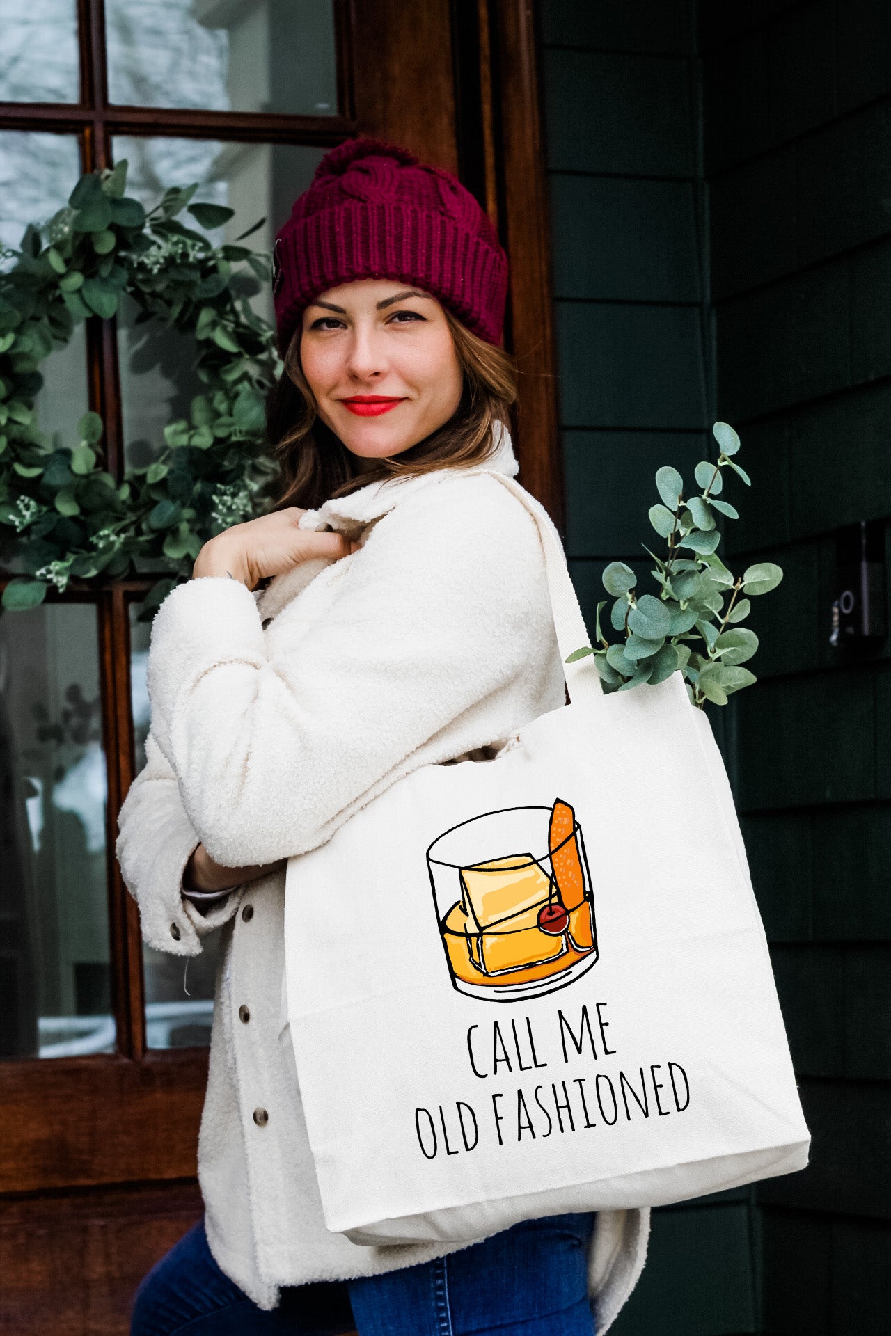 a woman carrying a white bag with a picture of a glass of whiskey