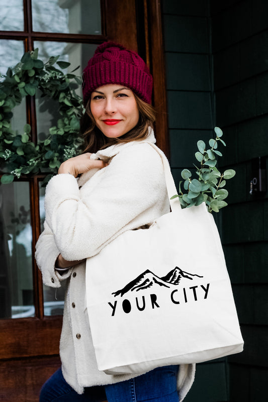 a woman carrying a white bag with the words your city printed on it