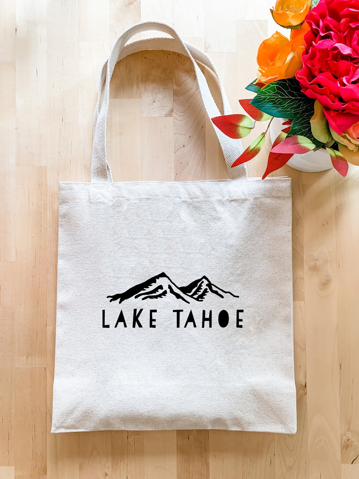 a lake tahoe tote bag next to a bouquet of flowers