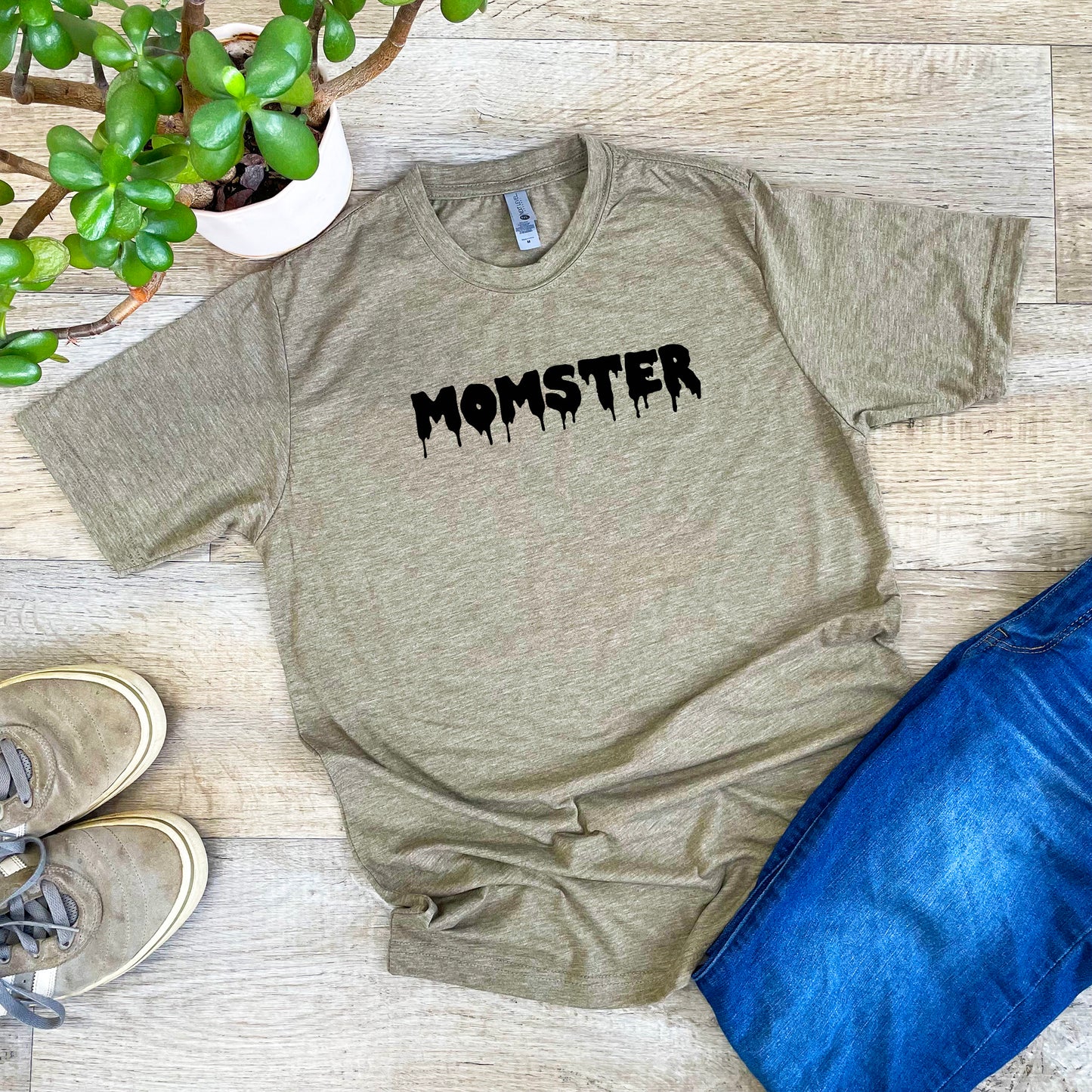a t - shirt with the word monster on it next to a potted plant