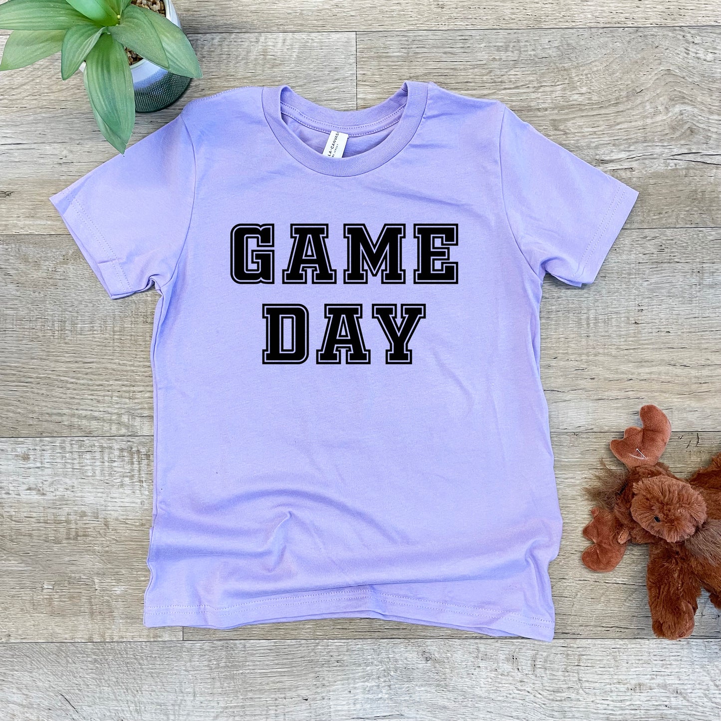a purple shirt that says game day next to a teddy bear