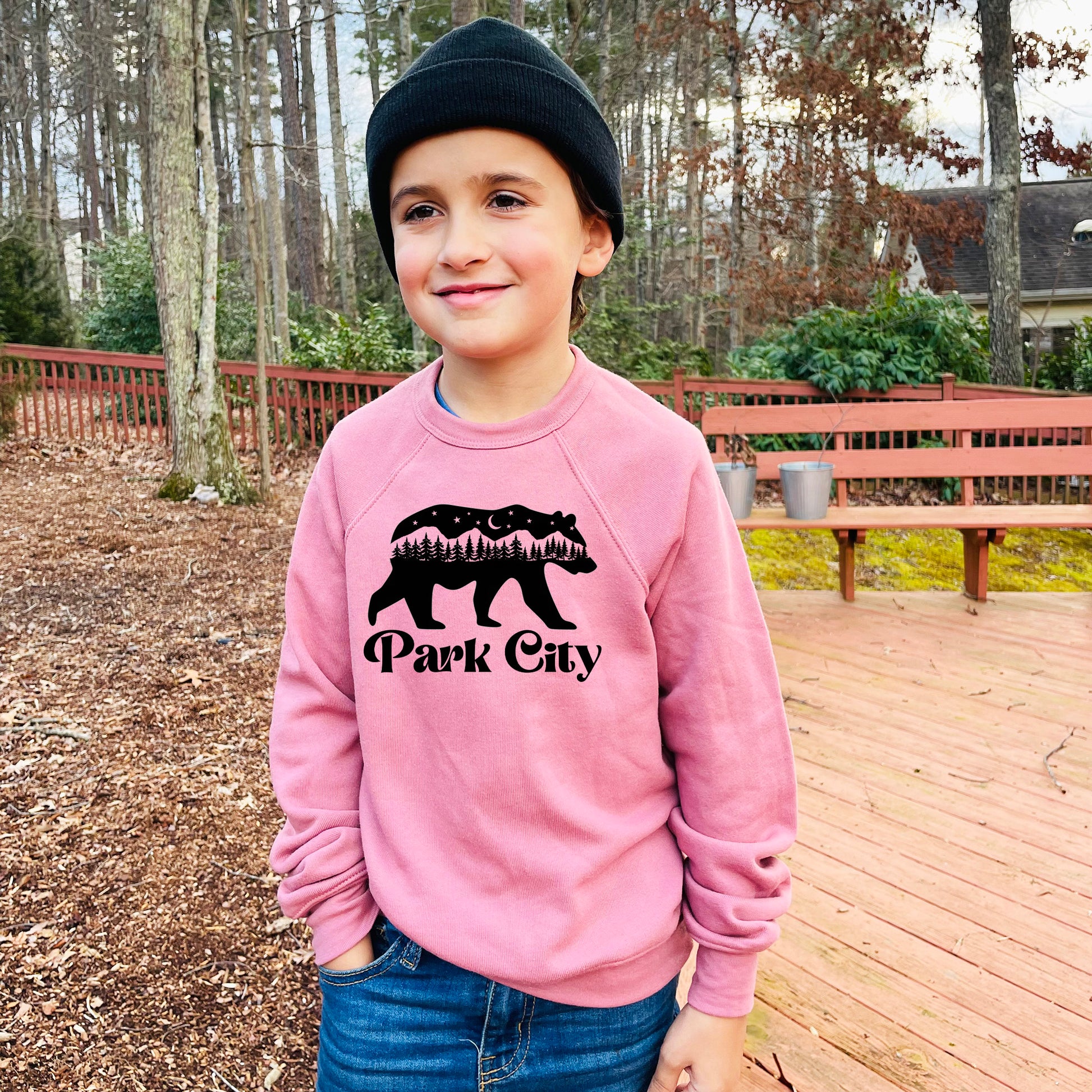 a young boy wearing a pink park city sweatshirt