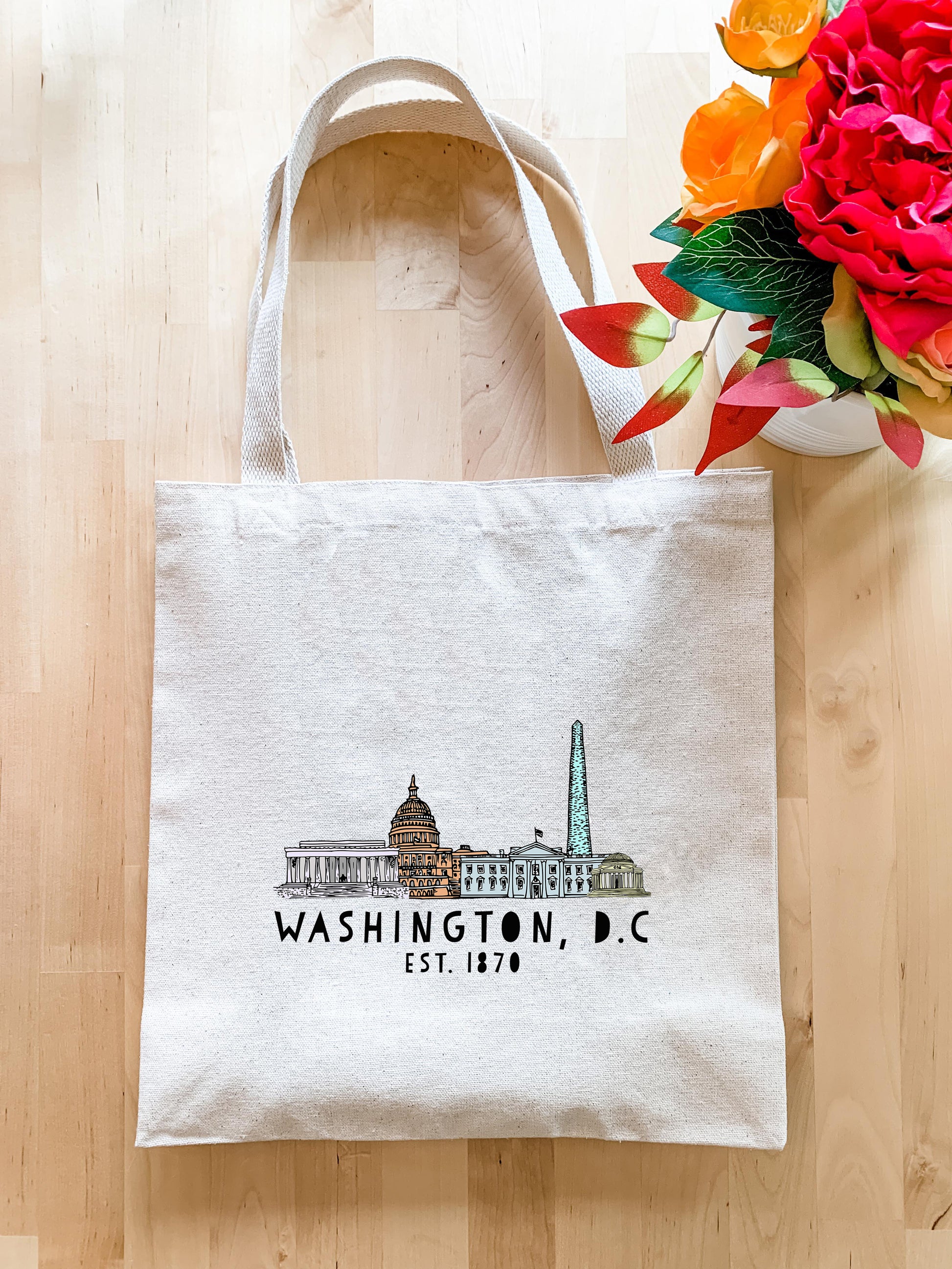 a white bag with washington dc on it next to a vase of flowers