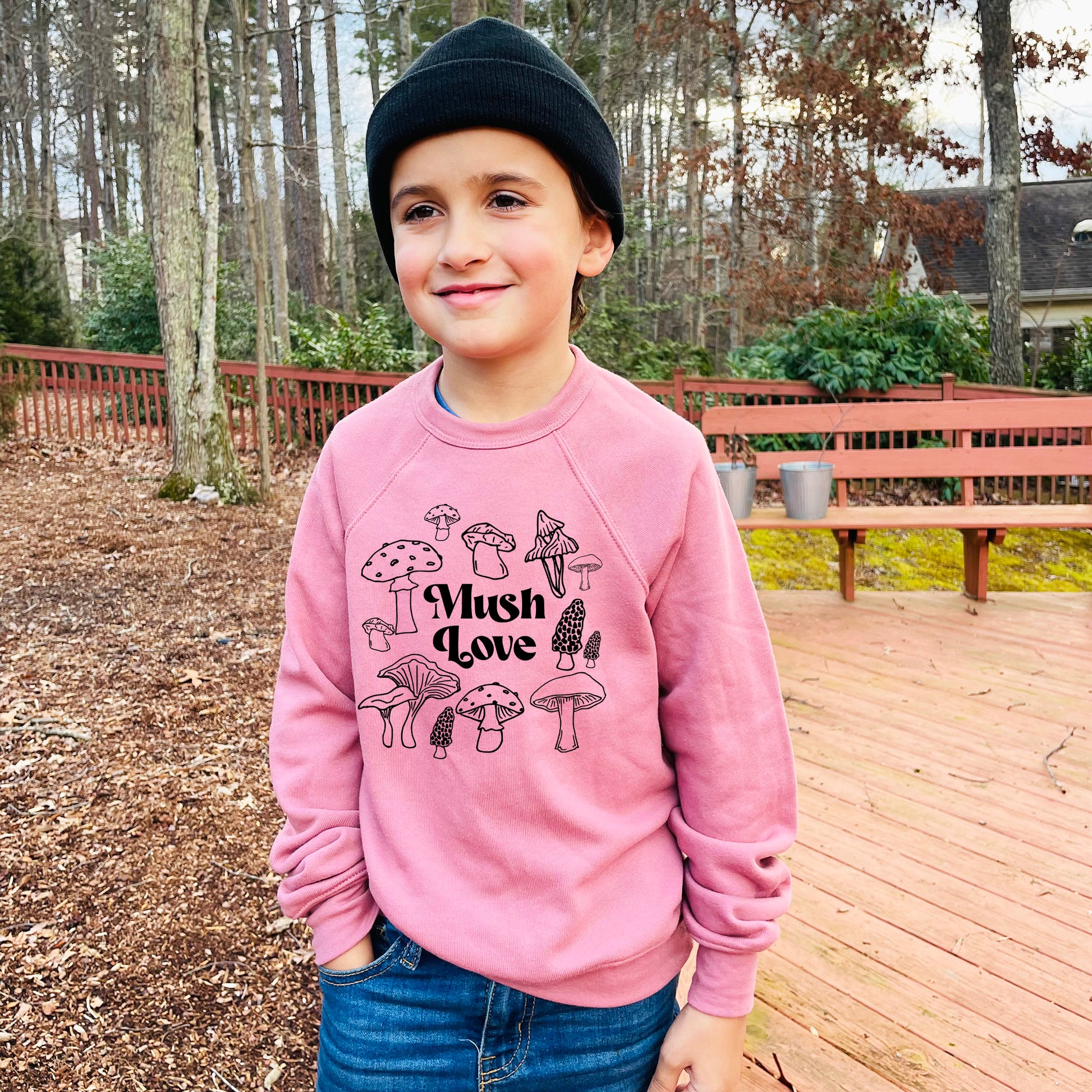 a young boy wearing a pink sweatshirt and a black hat