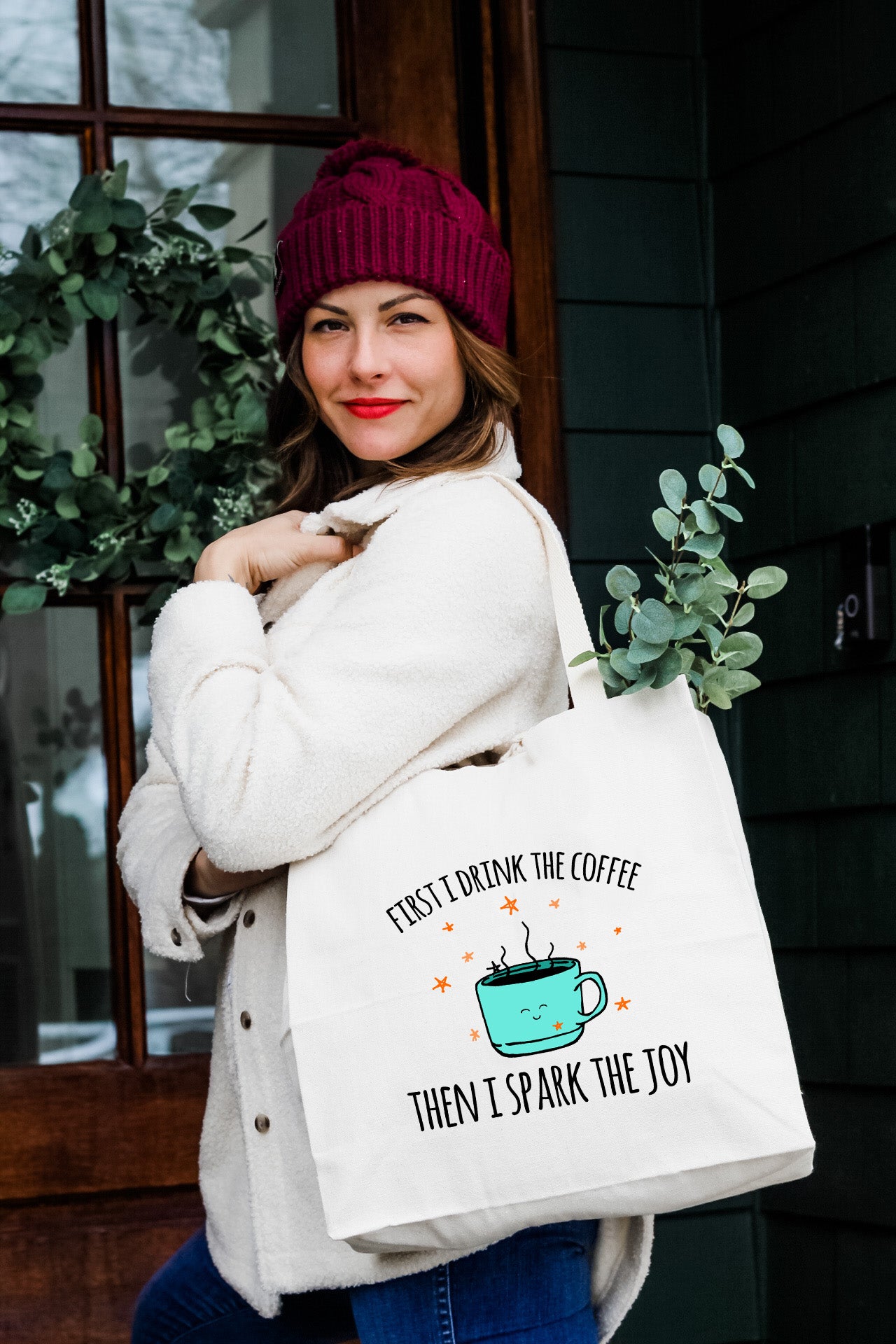 a woman carrying a bag that says first coffee then i spark the joy