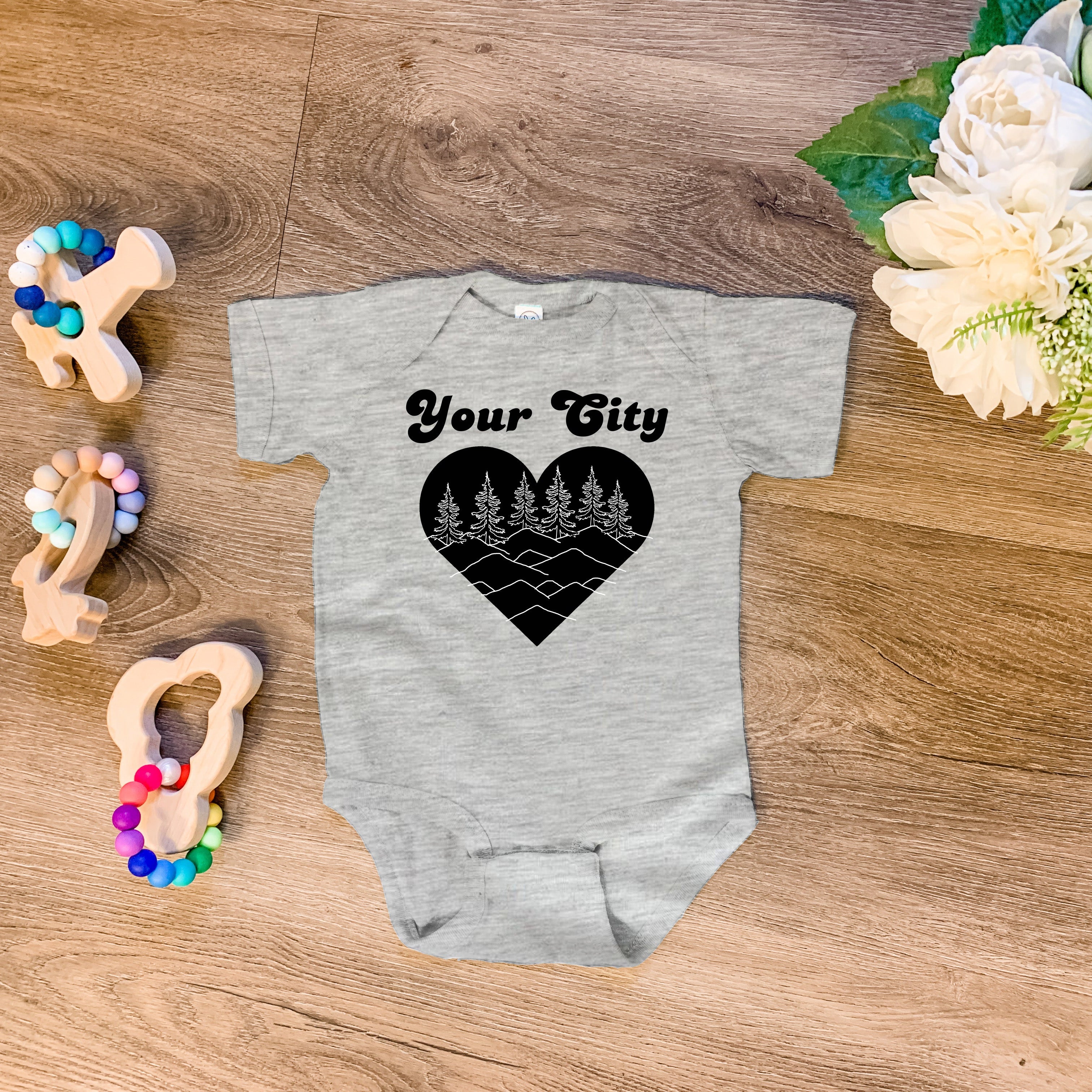 a baby bodysuit with a heart and trees on it