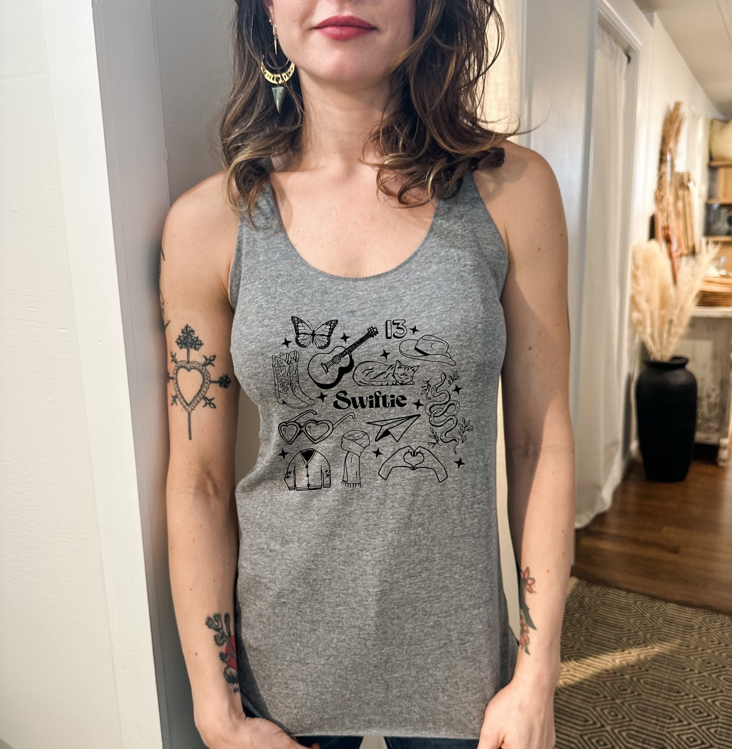 a woman wearing a tank top with a tattoo on her arm