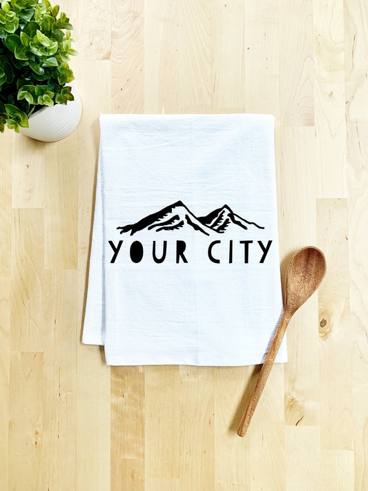 a tea towel that says your city next to a wooden spoon