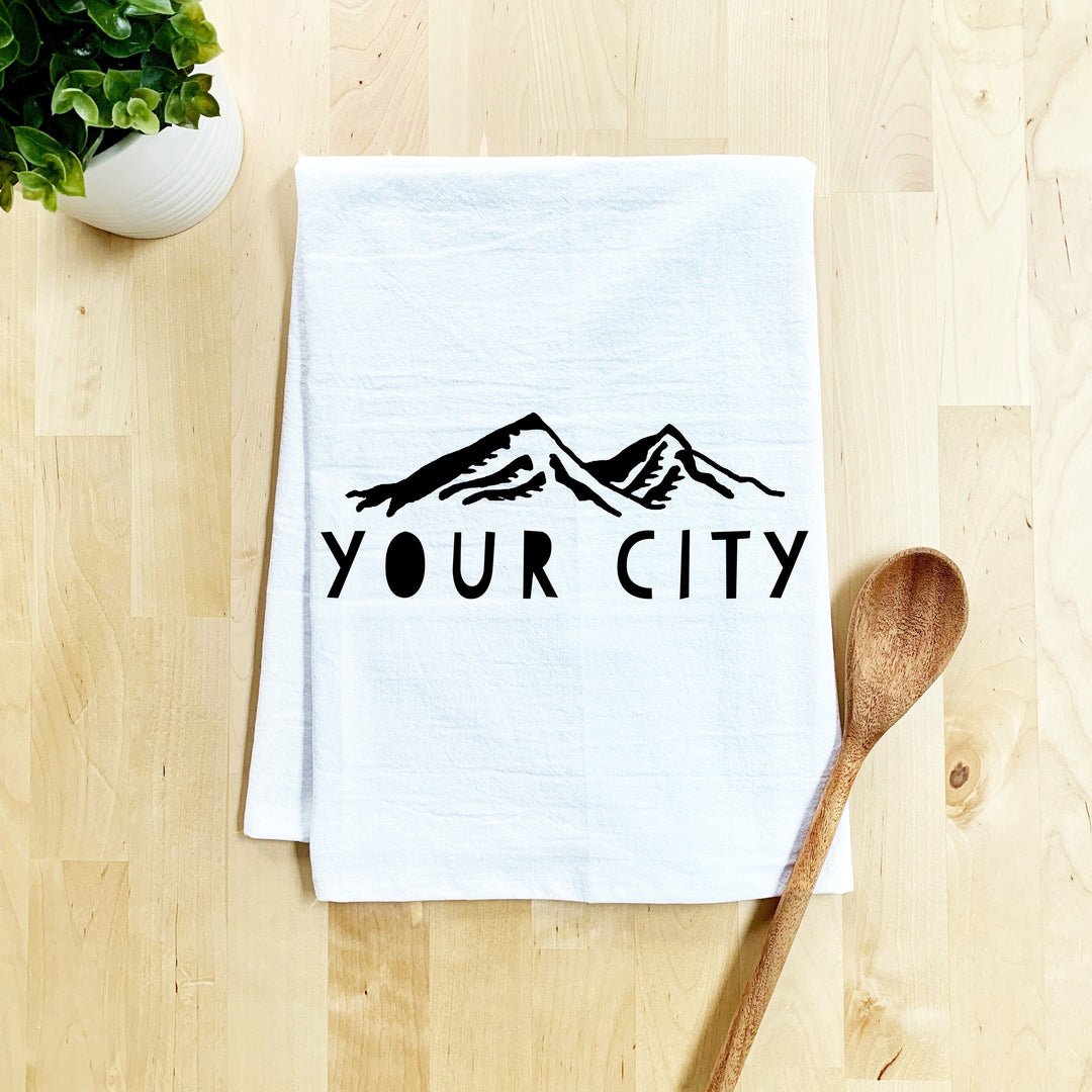 a tea towel that says your city next to a wooden spoon