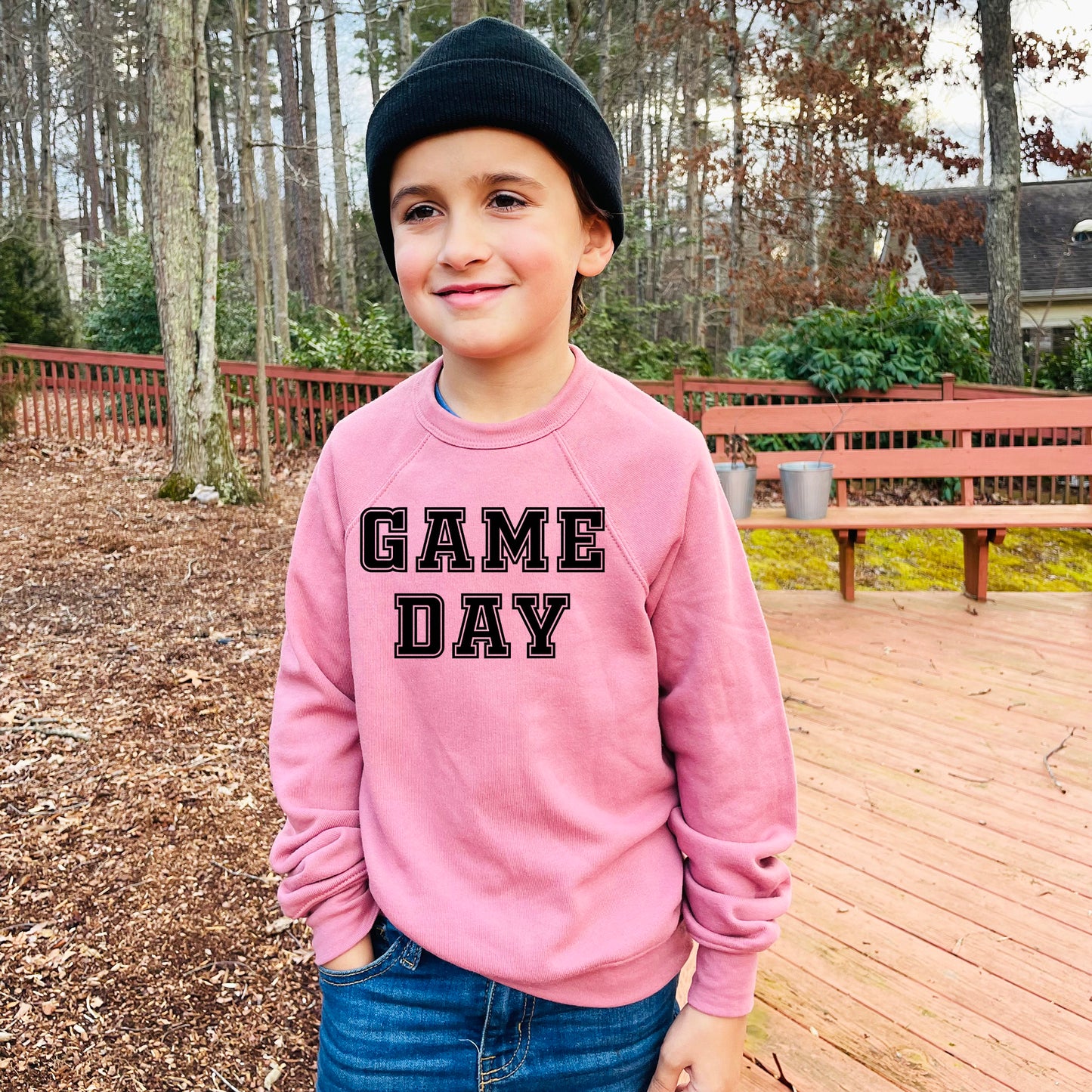 a young boy wearing a pink game day sweatshirt