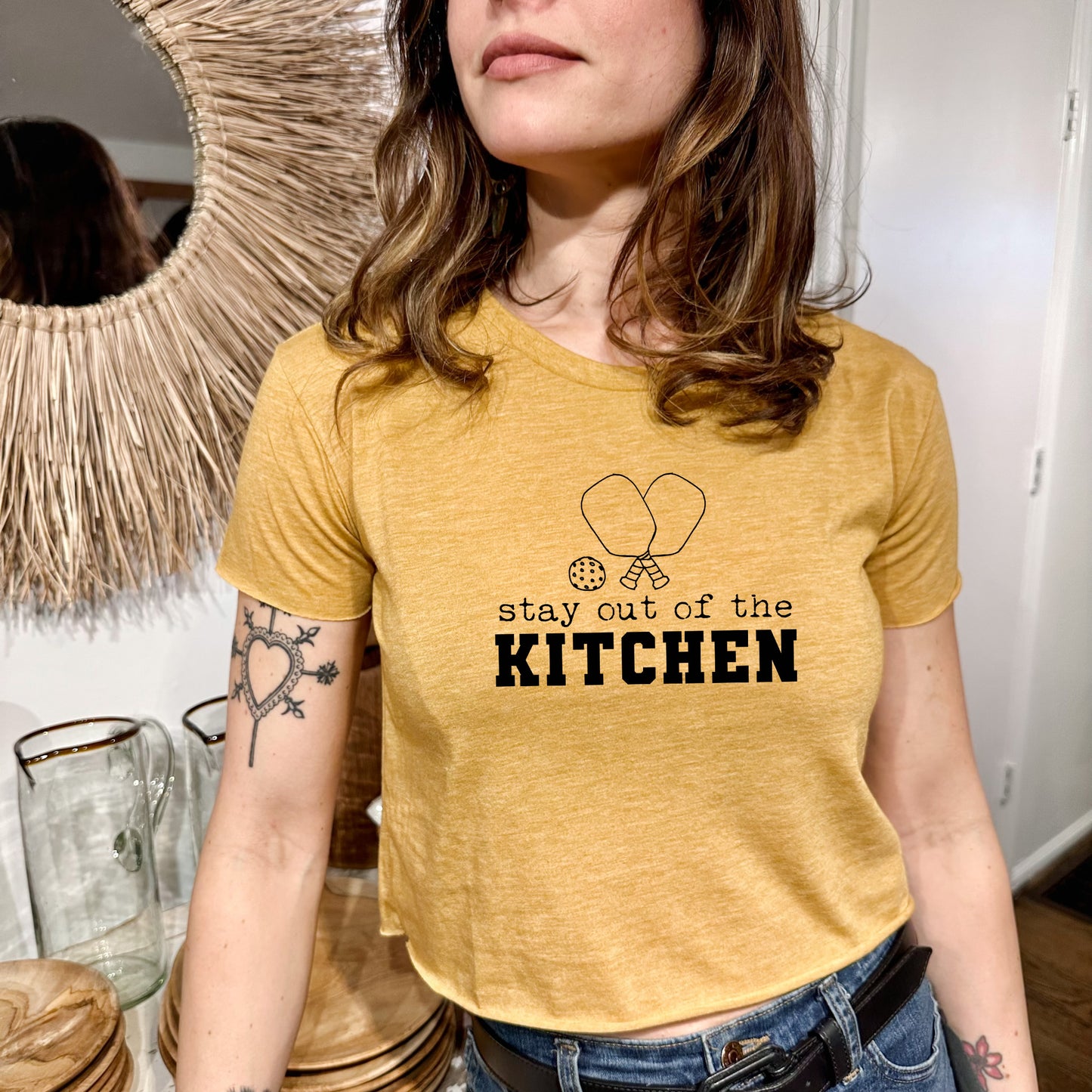 a woman wearing a yellow shirt that says stay out of the kitchen