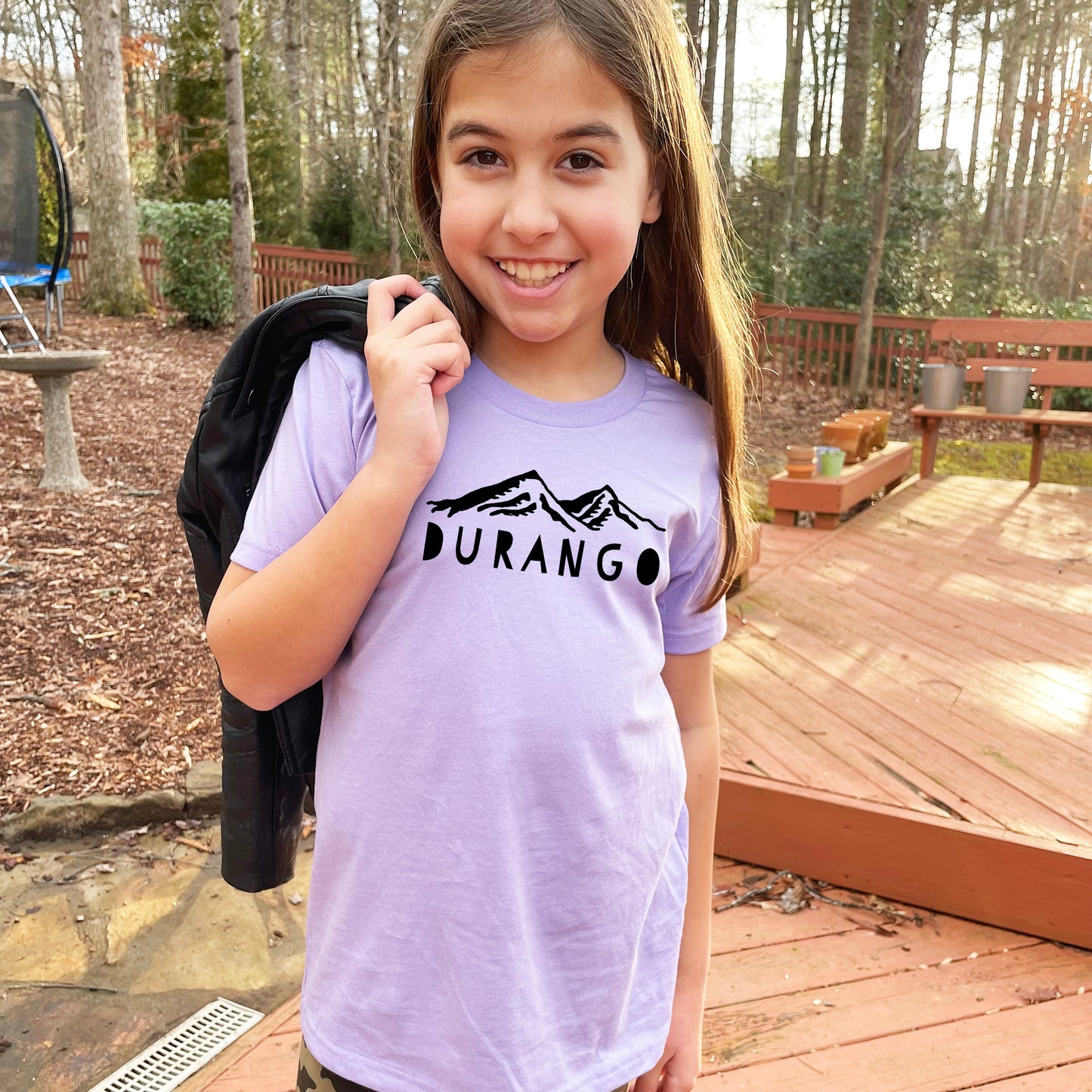 a young girl holding a backpack and smiling