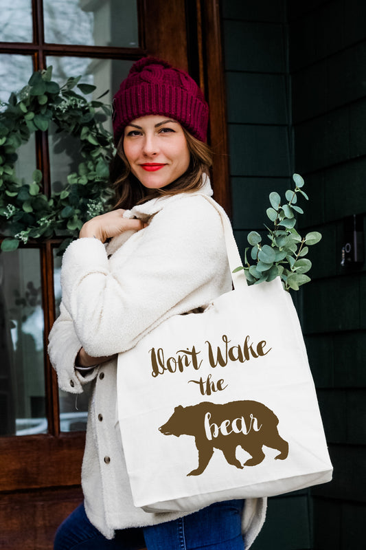 a woman carrying a bag that says don't wake the bear