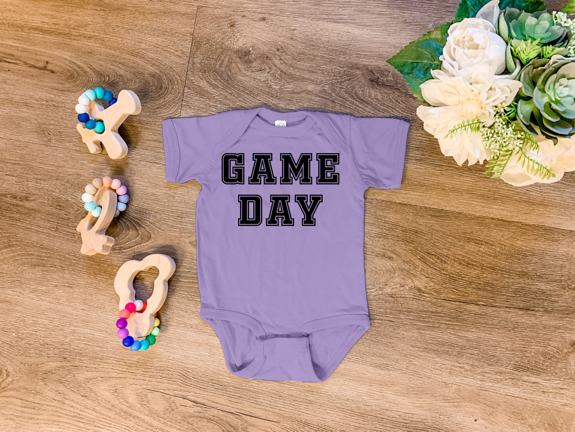 a baby bodysuit that says game day next to some toys