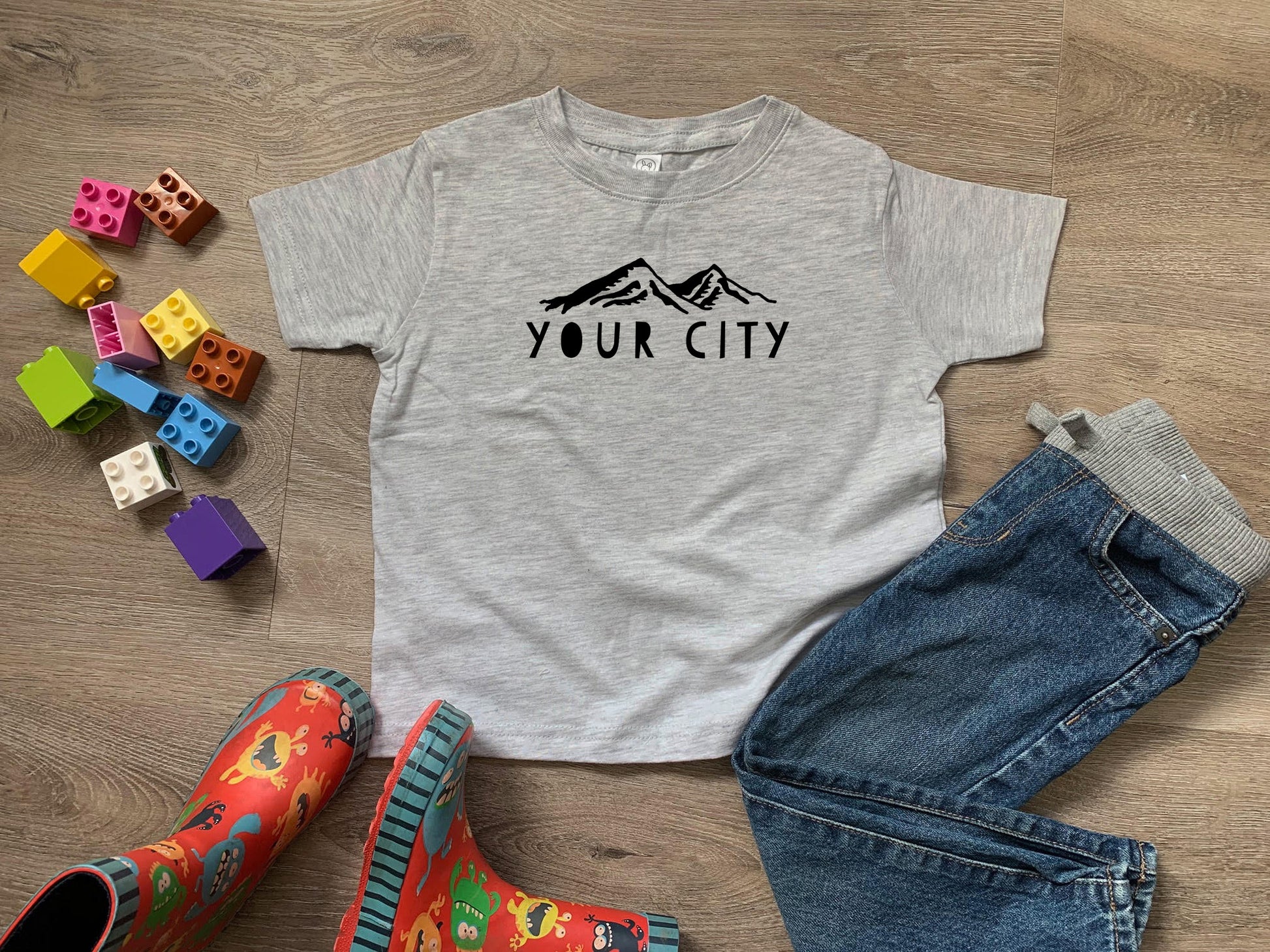a t - shirt that says your city next to a pair of jeans and rubber