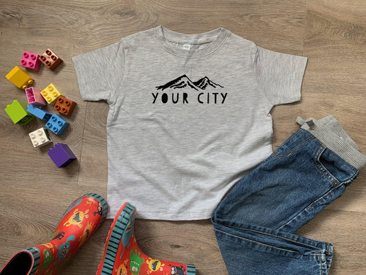 a t - shirt that says your city next to a pair of jeans and rubber