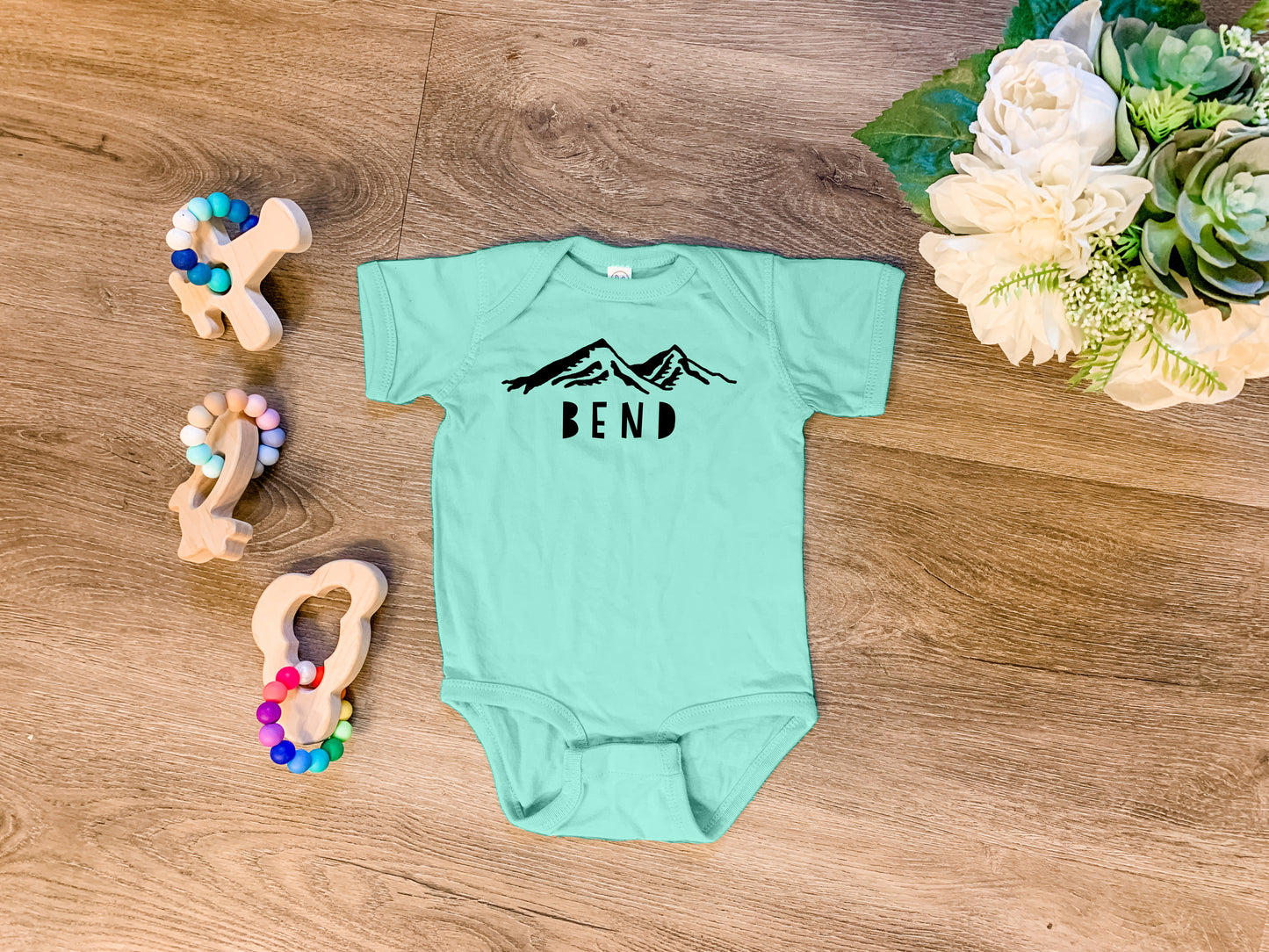 a baby bodysuit with the word bend on it next to a pair of scissors