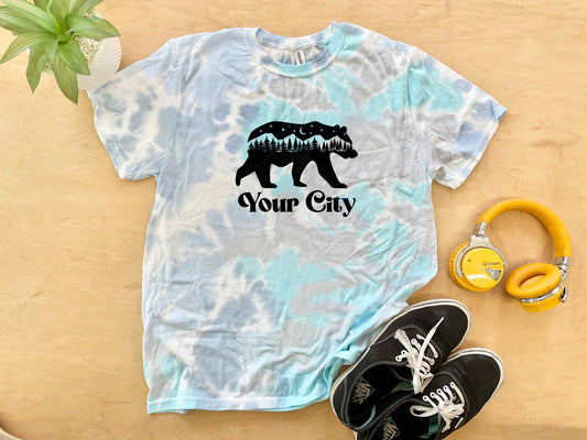 a t - shirt with a bear on it next to headphones and a pair