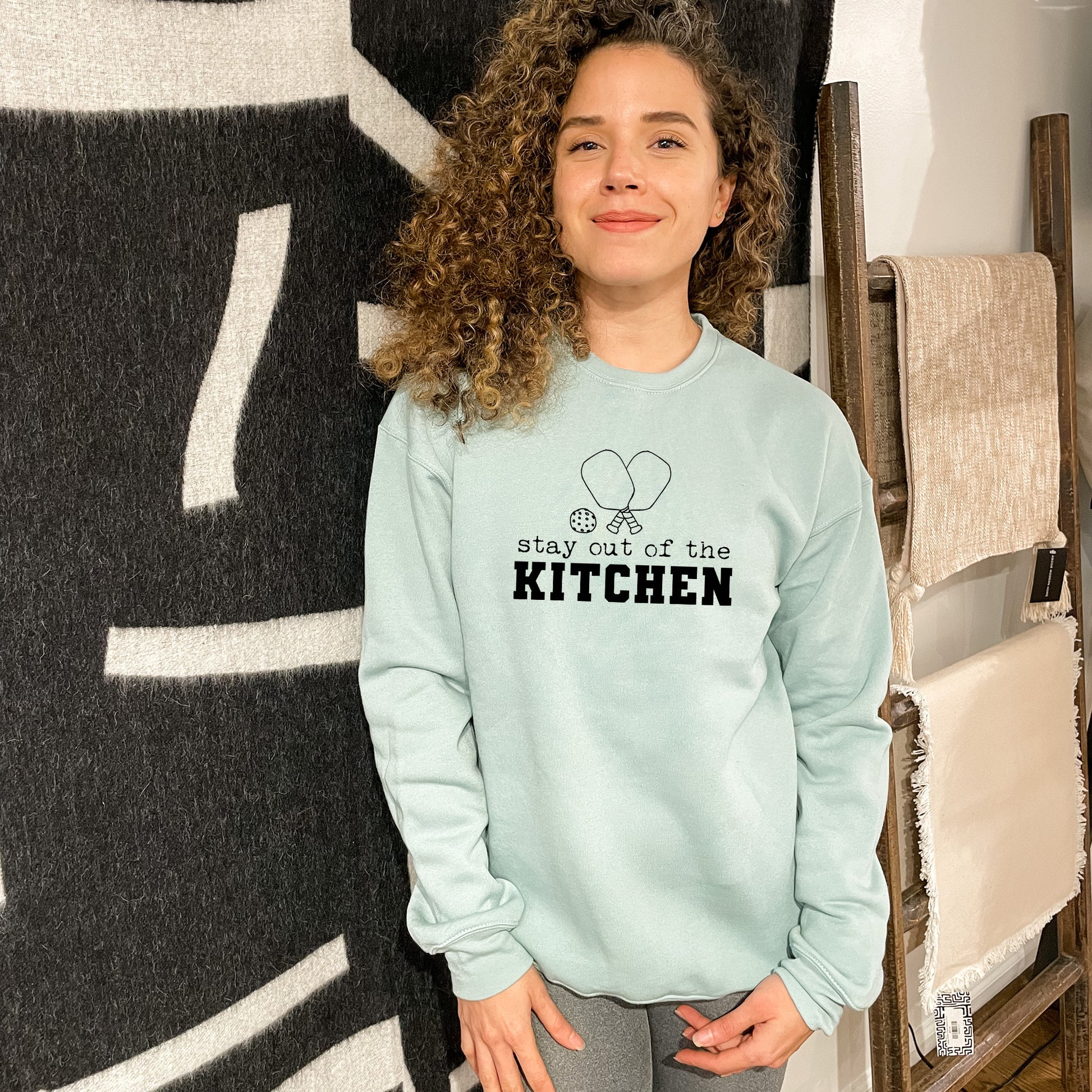 a woman standing in front of a kitchen sign
