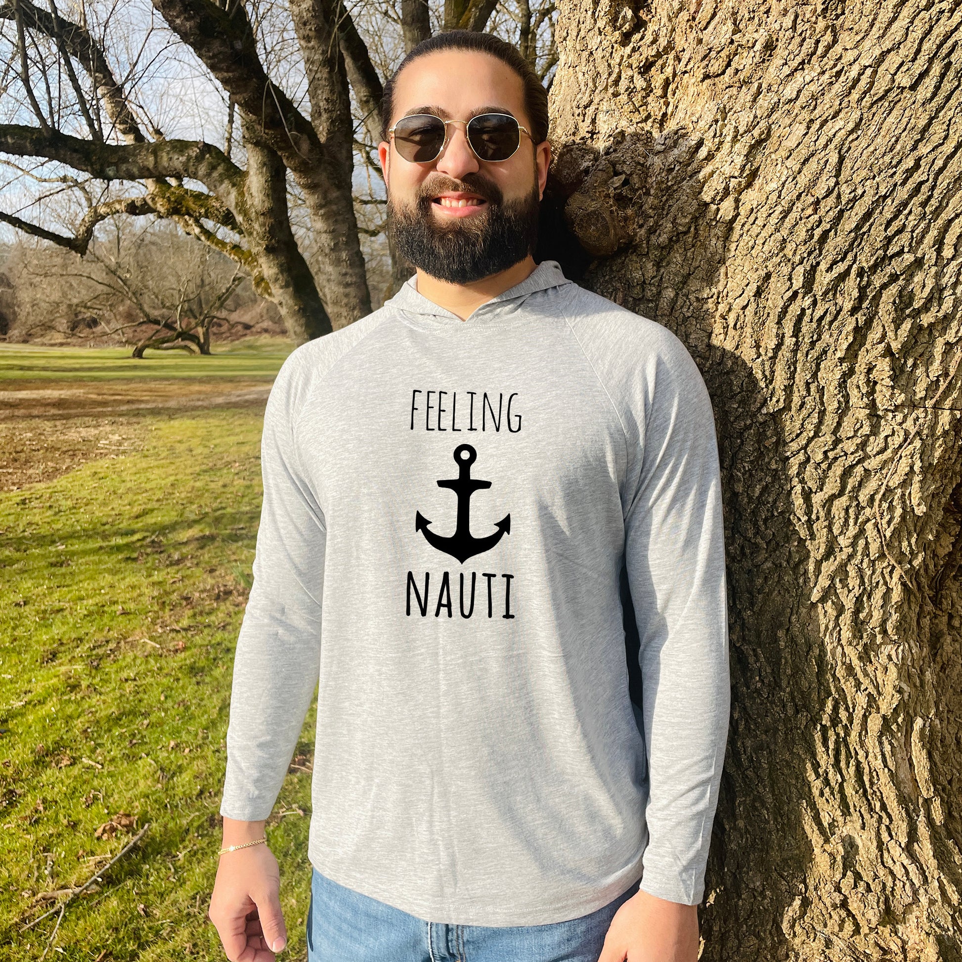 a man standing next to a tree wearing a shirt that says feeling nautit