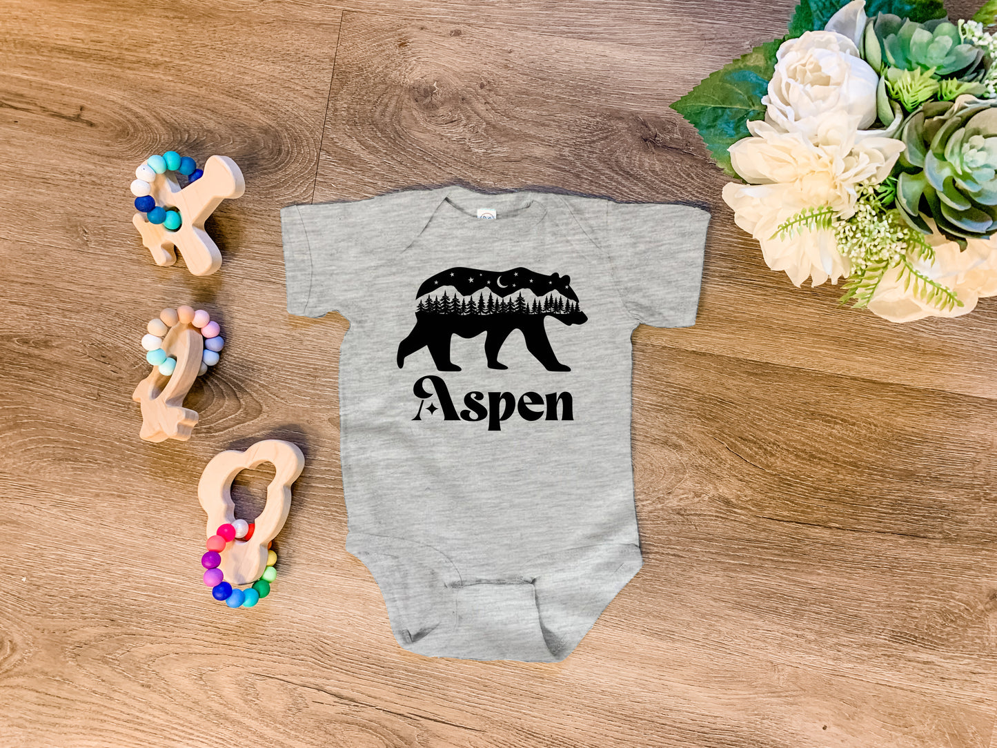 a baby bodysuit with a bear and trees on it