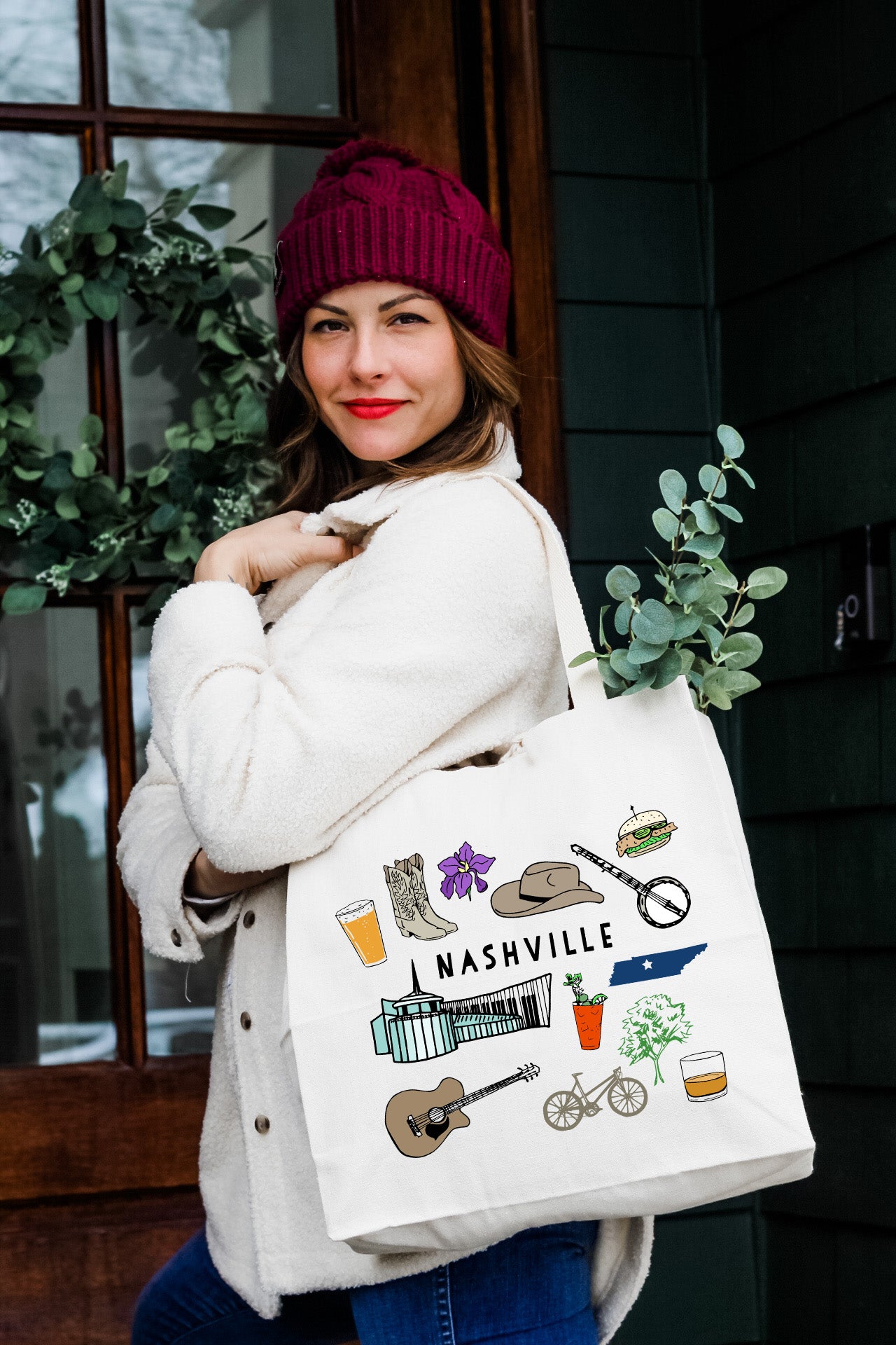 a woman carrying a white bag with a picture of nashville on it