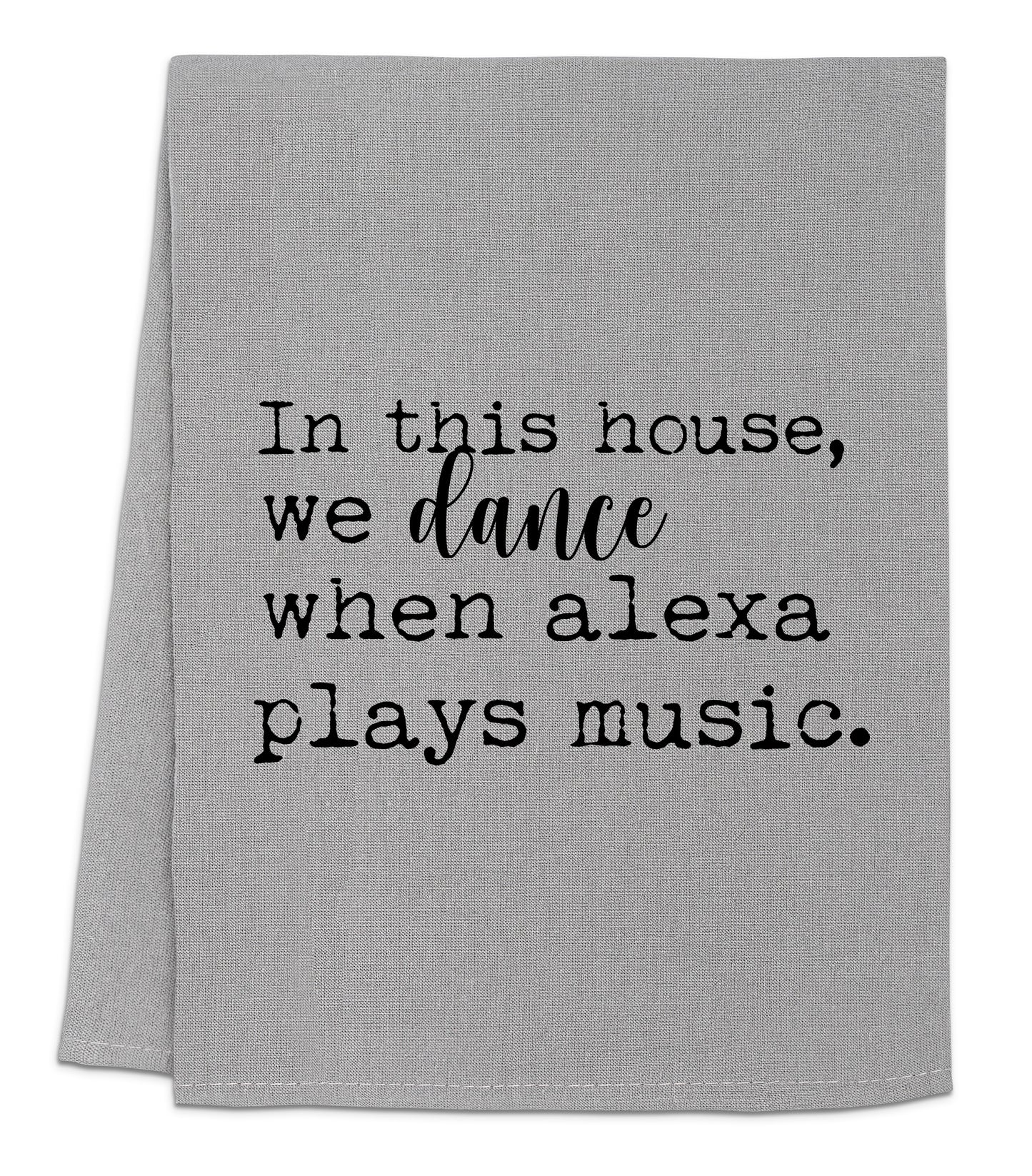 a gray towel with black lettering that says, in this house, we dance when