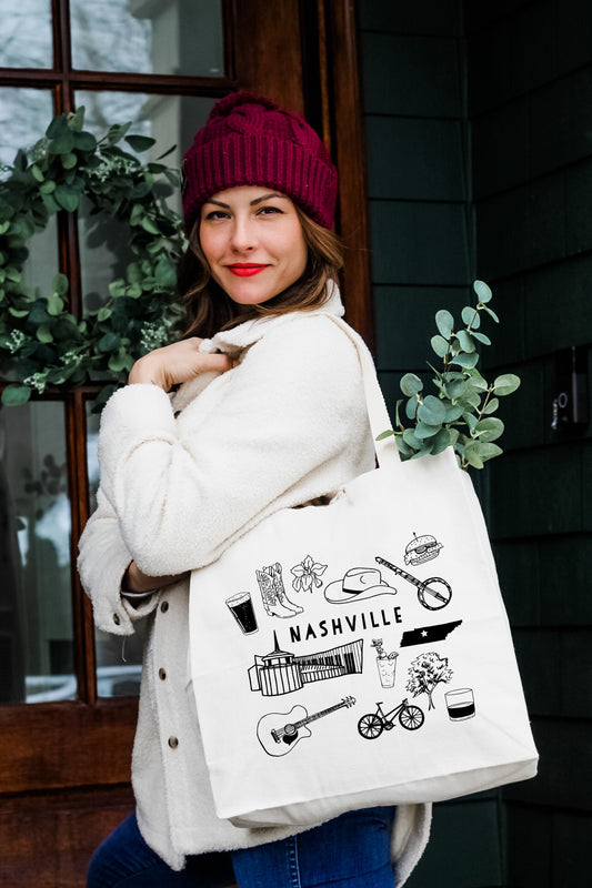 a woman carrying a white bag with a picture of nashville