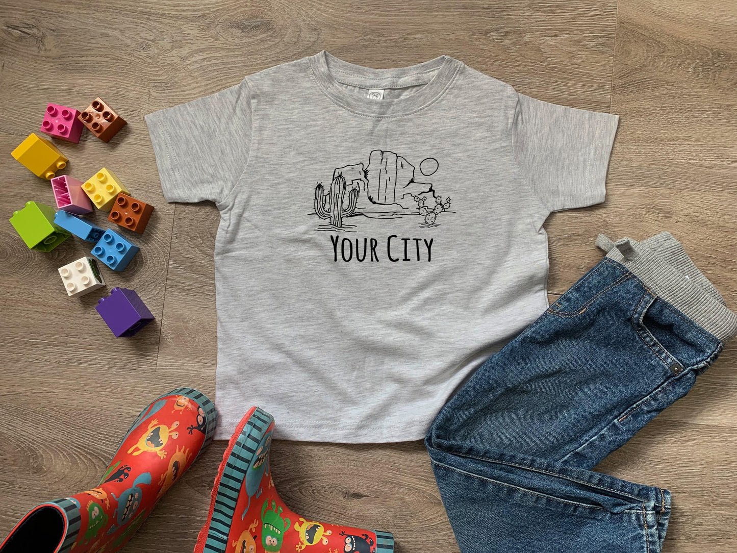 a t - shirt that says your city on it next to a pair of jeans